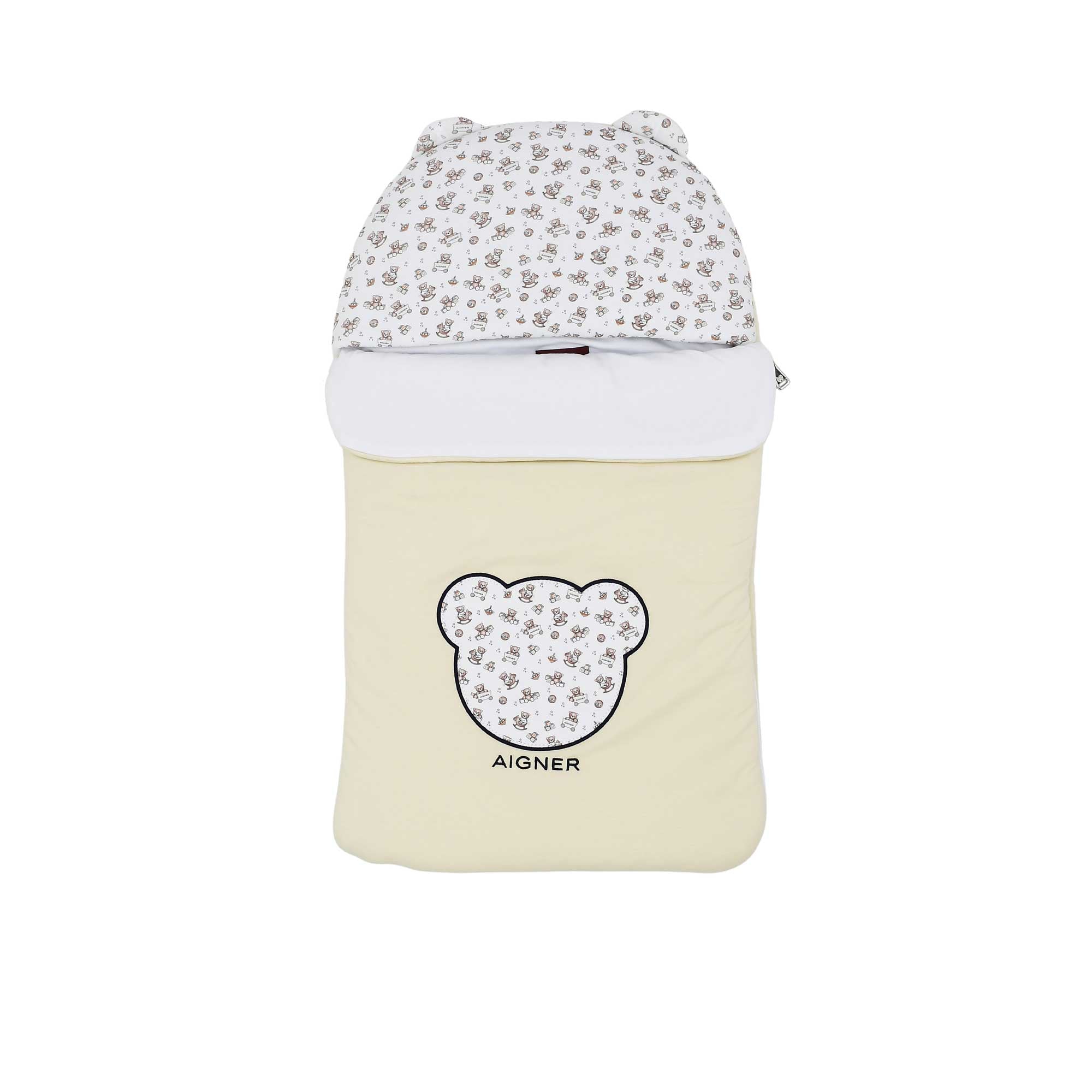 Front view of a cream Aigner Kids baby nest showing a bear-shaped applique with a wagon print, matching printed hood with 3D ears, and the Aigner brand name