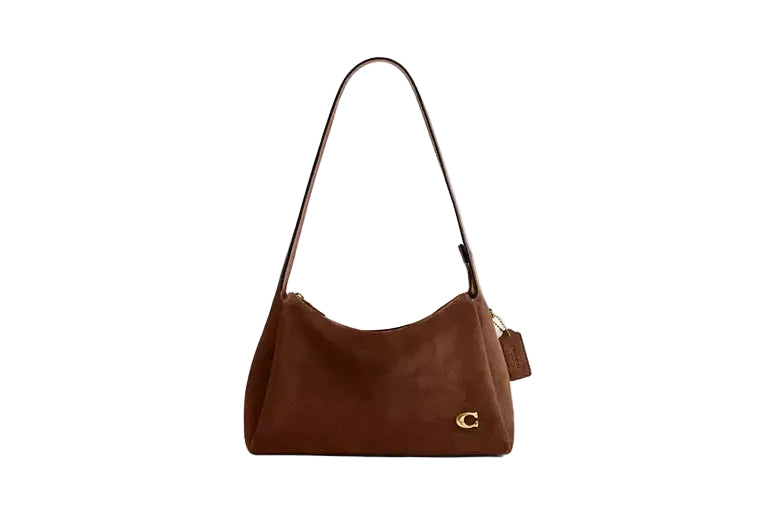 Front-facing view of the Coach Juliet shoulder bag in chestnut suede featuring a gold-tone "C" logo and a matching leather hangtag.