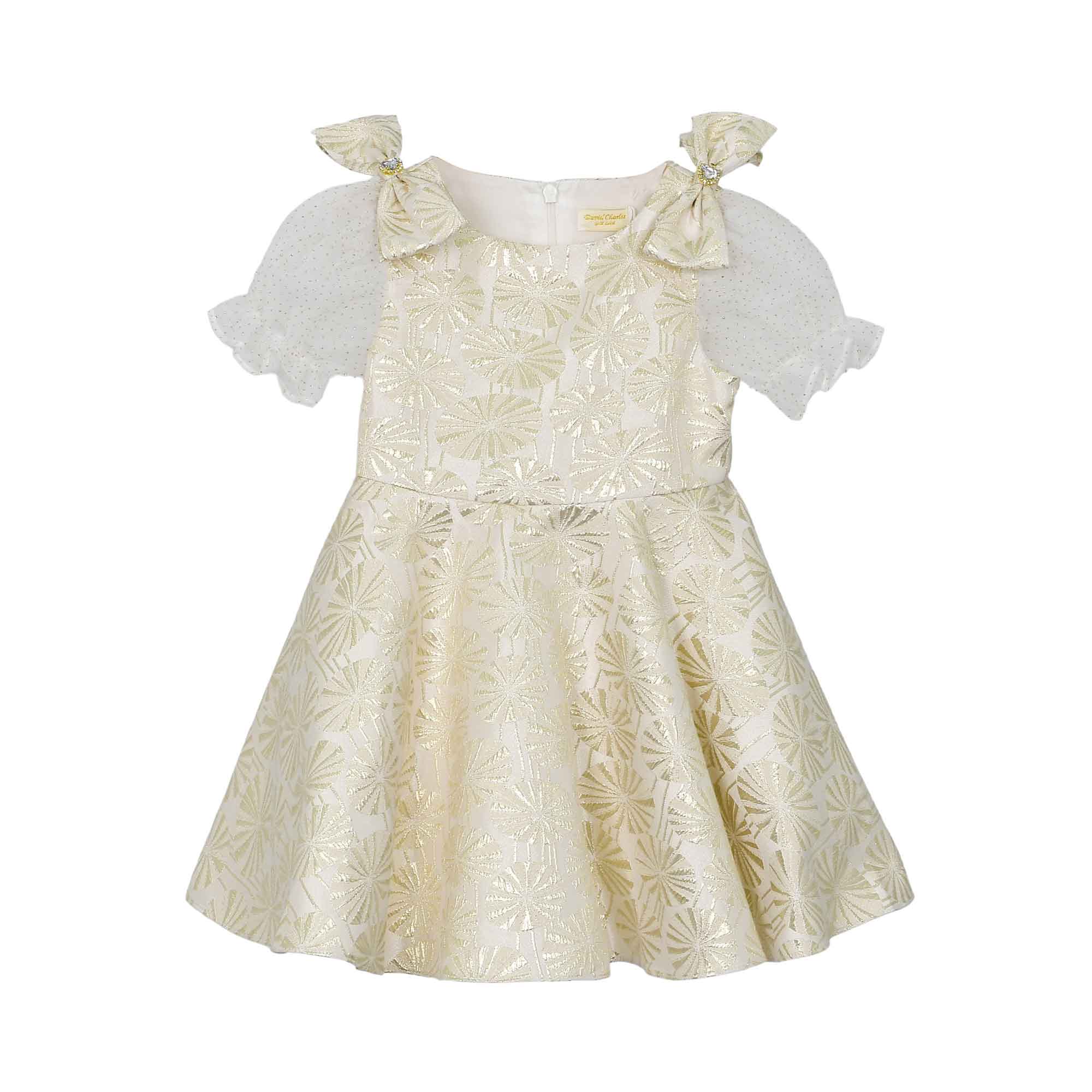 Front view of a David Charles girls' ivory dress with gold metallic starburst patterns, sheer glitter puff sleeves, and jeweled shoulder bows.