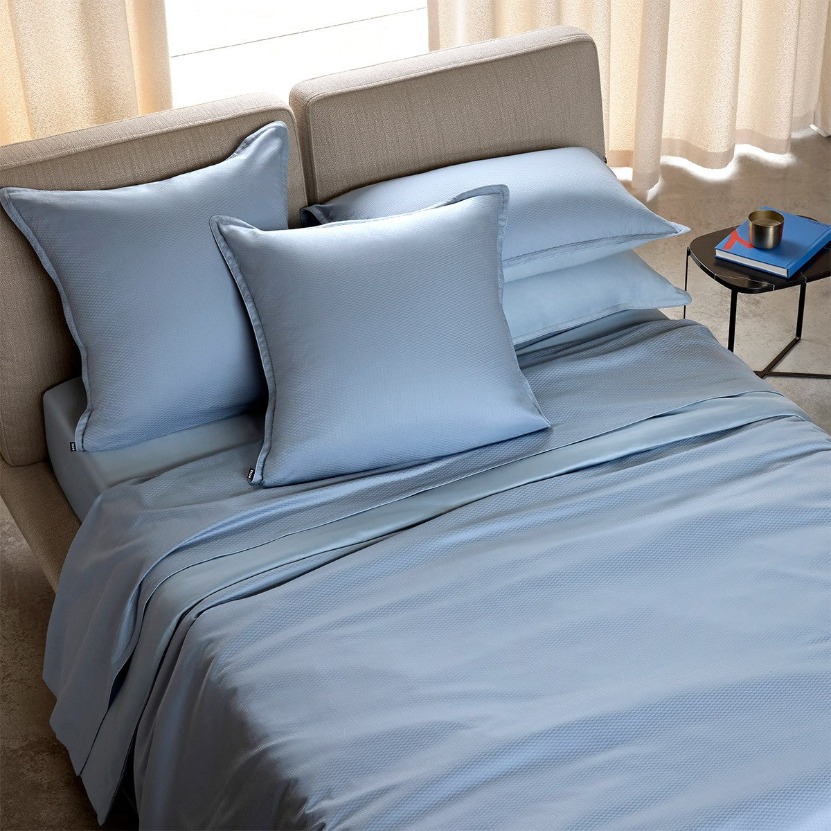Light blue Hugo Boss Loft Horizon bedding set with textured duvet cover, flat sheet, and four pillowcases on a bed.