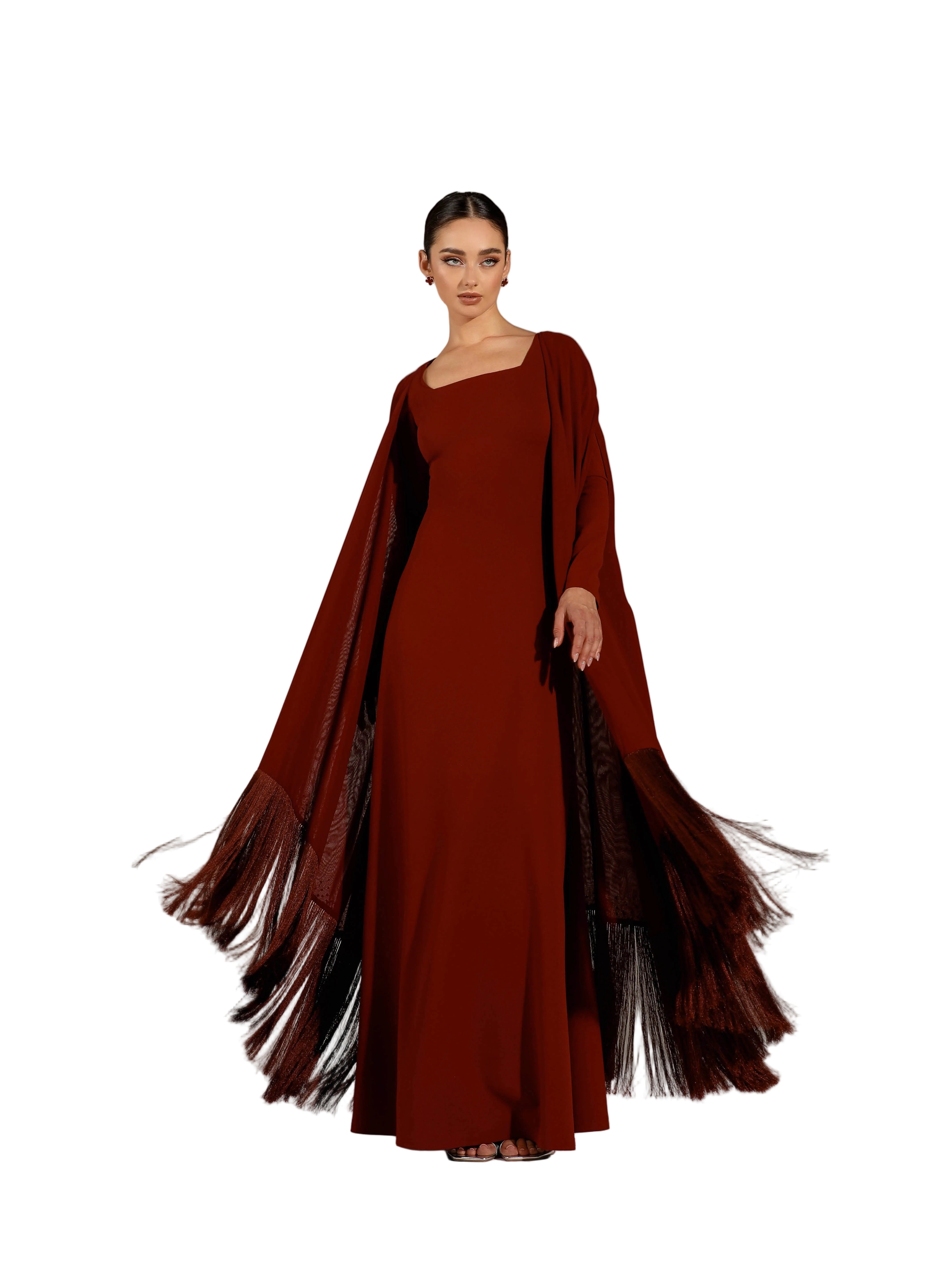 A woman modeling a Velvety brand burgundy two-piece set consisting of a sleek square-neck column dress and a matching long-sleeved sheer outer cape with heavy fringe detailing at the hem.