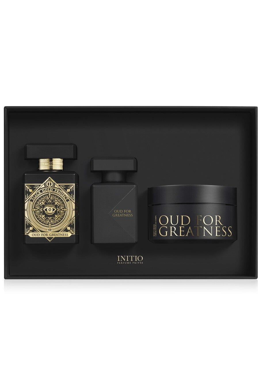 Initio Parfums Privés Oud for Greatness luxury gift set cleanly nestled inside a matte black insert, displaying the signature geometric gold-detailed perfume bottle, a sleek black hair perfume bottle, and a matching body cream jar.