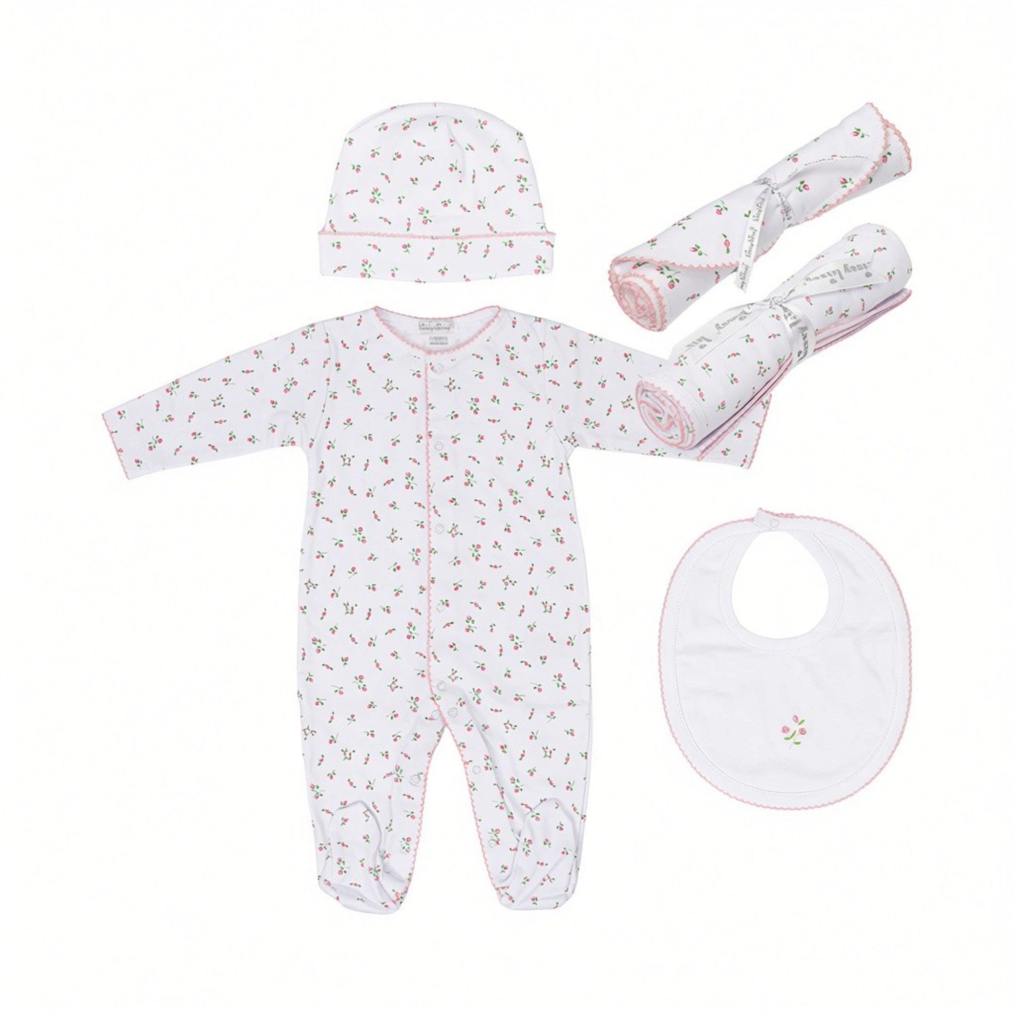 White newborn gift set with pink floral print, including a sleepsuit, hat, bib with embroidery, and two rolled blankets.