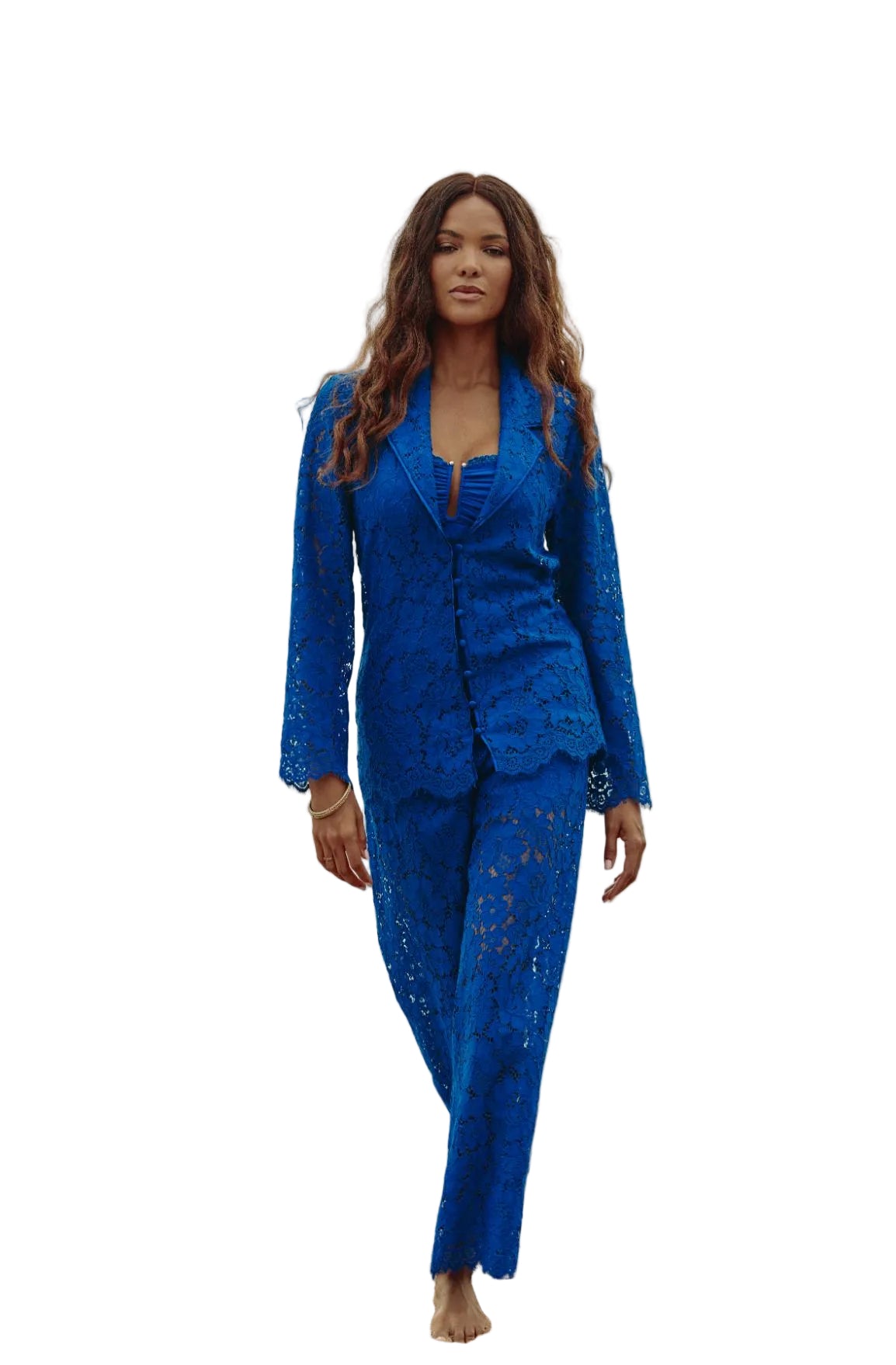 Model wearing Marjolaine royal blue sheer floral lace jacket and matching wide-leg trousers walking on beach available at BLUE SALON.