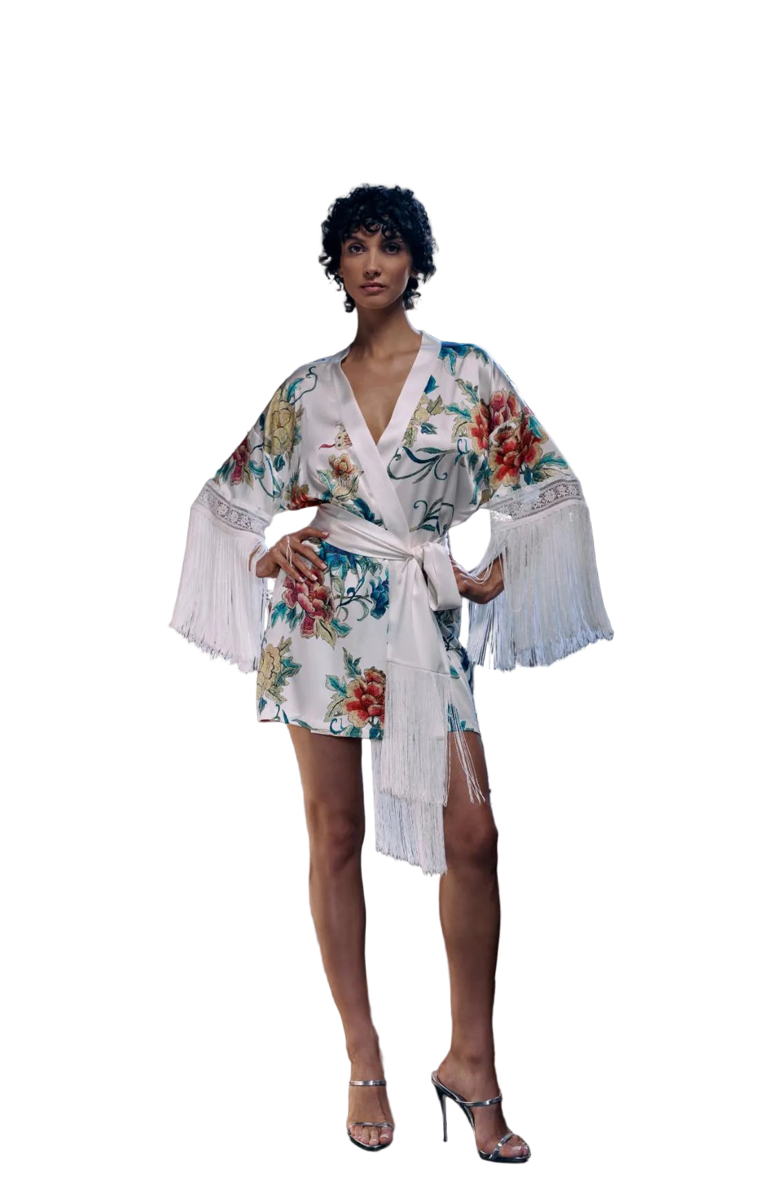 A woman models a white floral kimono-style robe with long white fringe sleeves and a matching tie belt, standing in front of a vintage clawfoot bathtub in a bathroom setting.