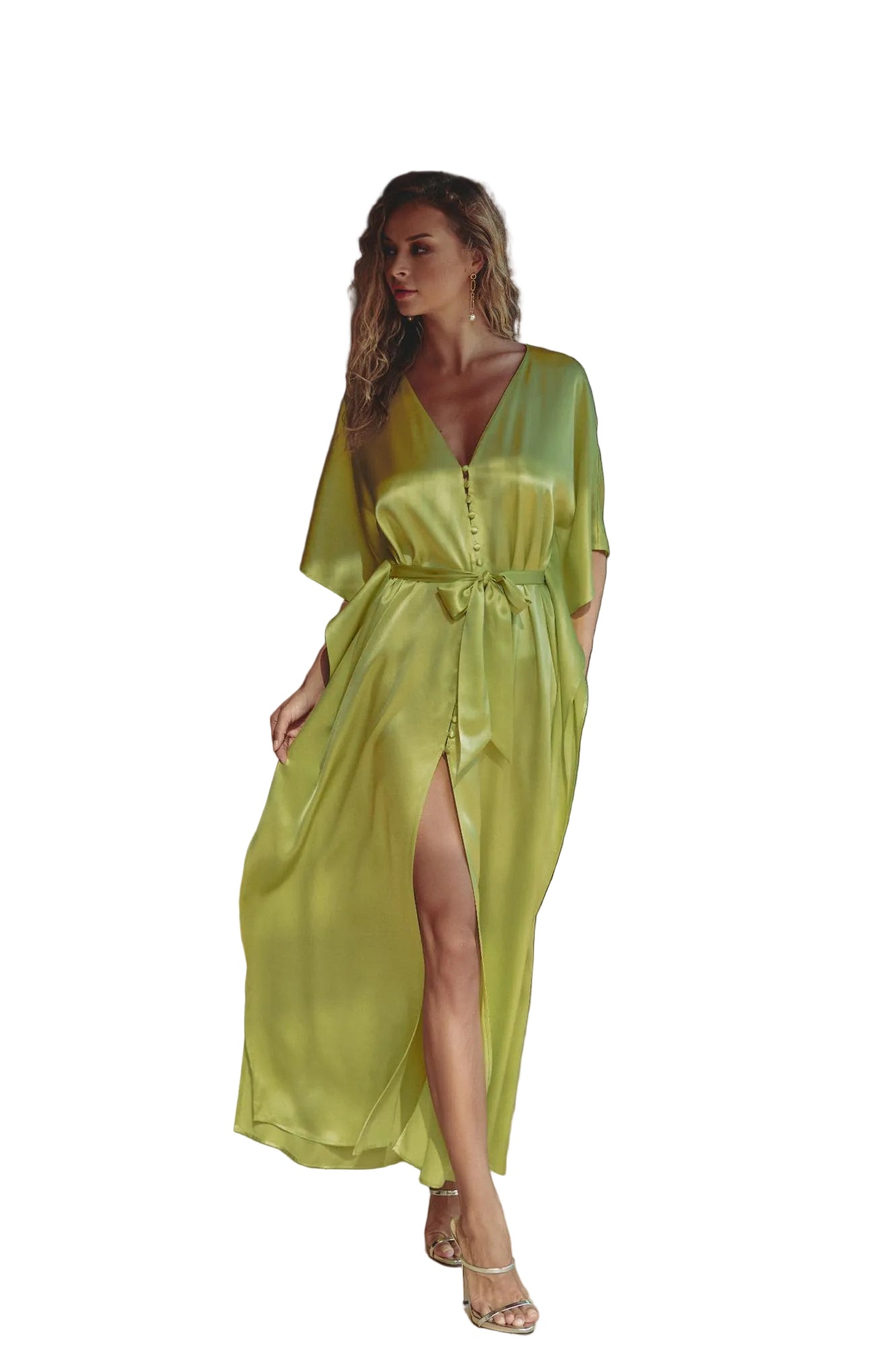 A woman models a flowing lime green satin maxi dress with a V-neckline, button-up front, and a matching tie belt, set in a sunlit indoor space with a balcony view.