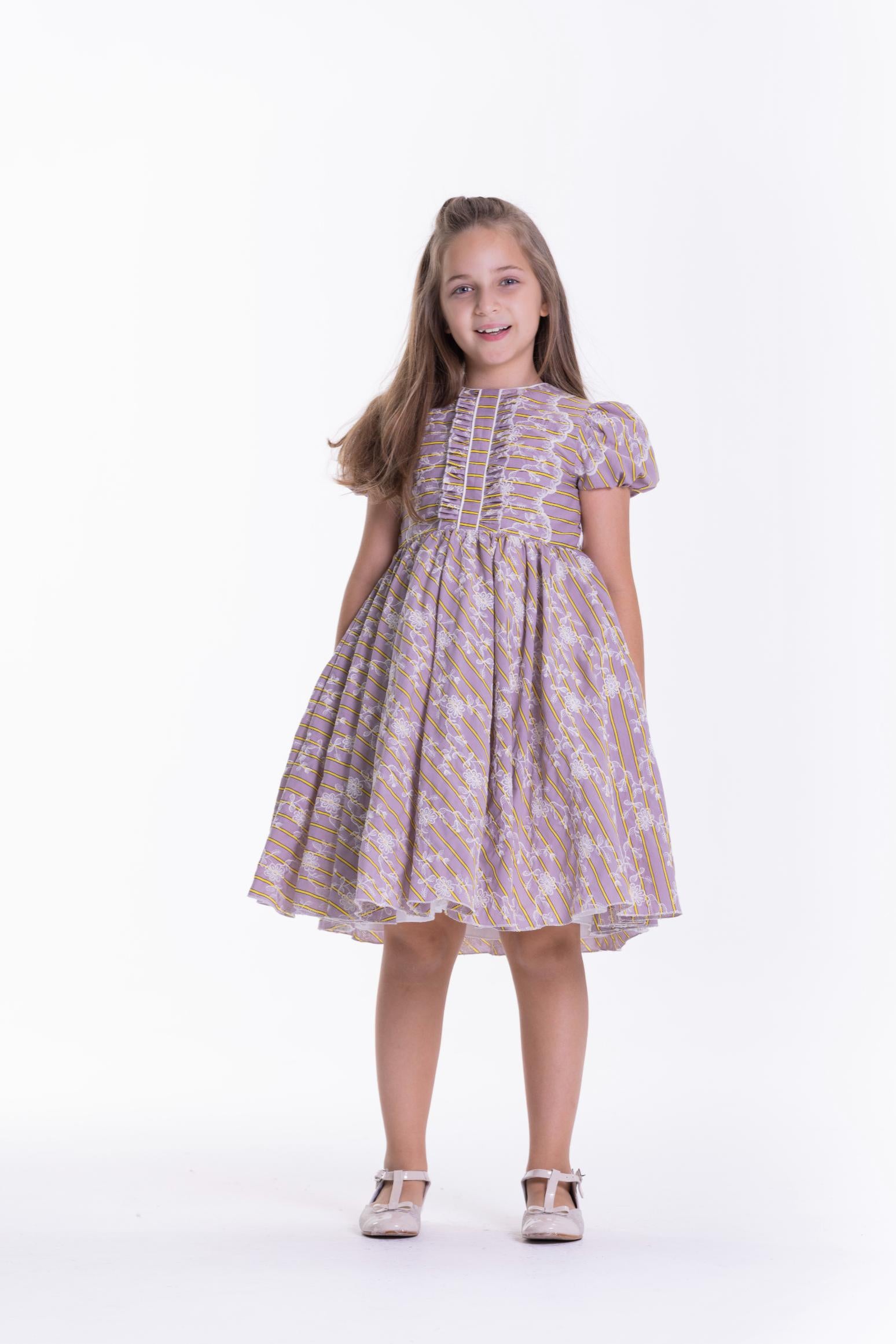 Purple kids' dress with white and yellow striped pattern, white floral overlay, ruffled bodice, and puffed short sleeves.