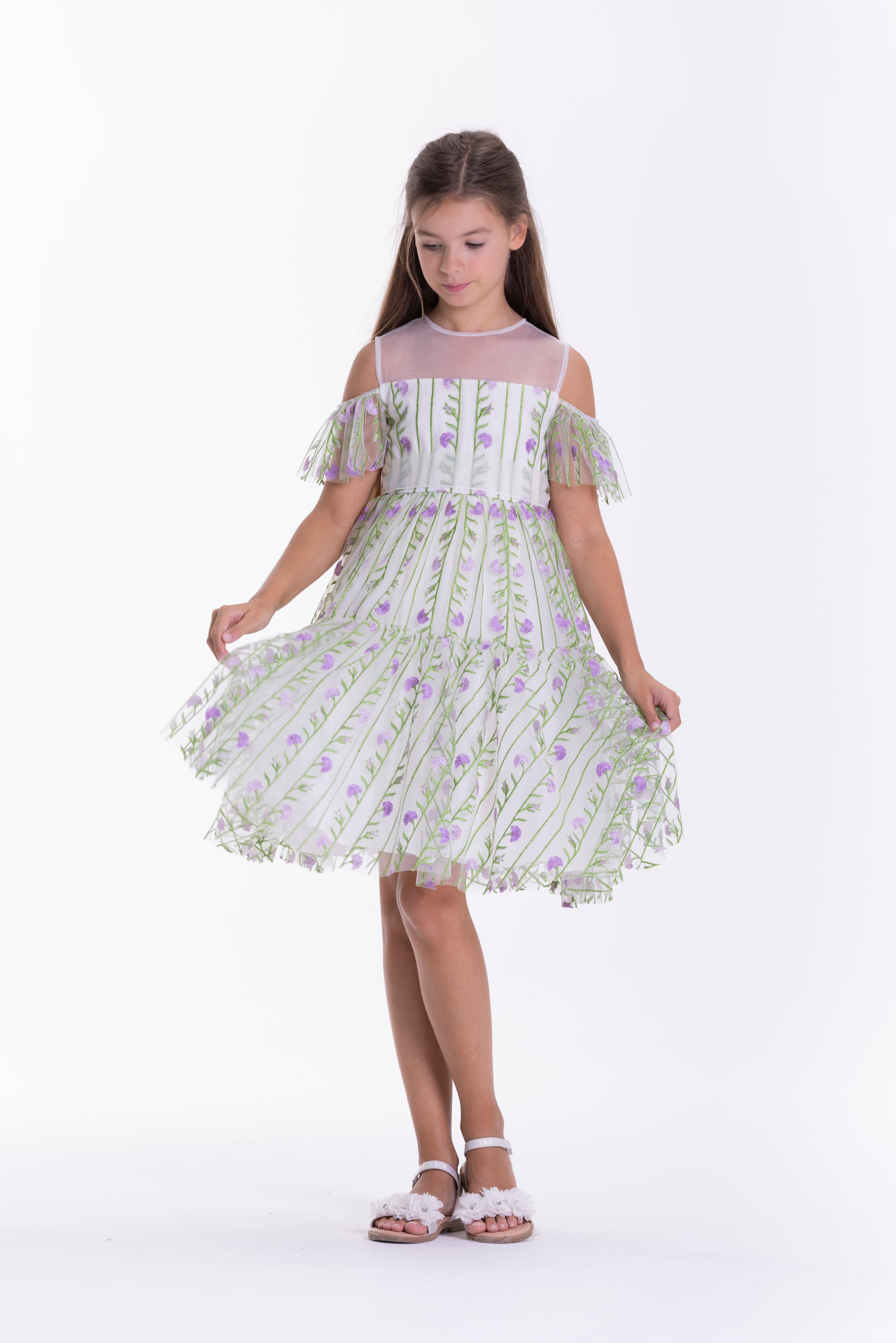 Off-white kids dress with sheer off-shoulder ruffled sleeves, sheer yoke, and vertical green and purple floral embroidery.