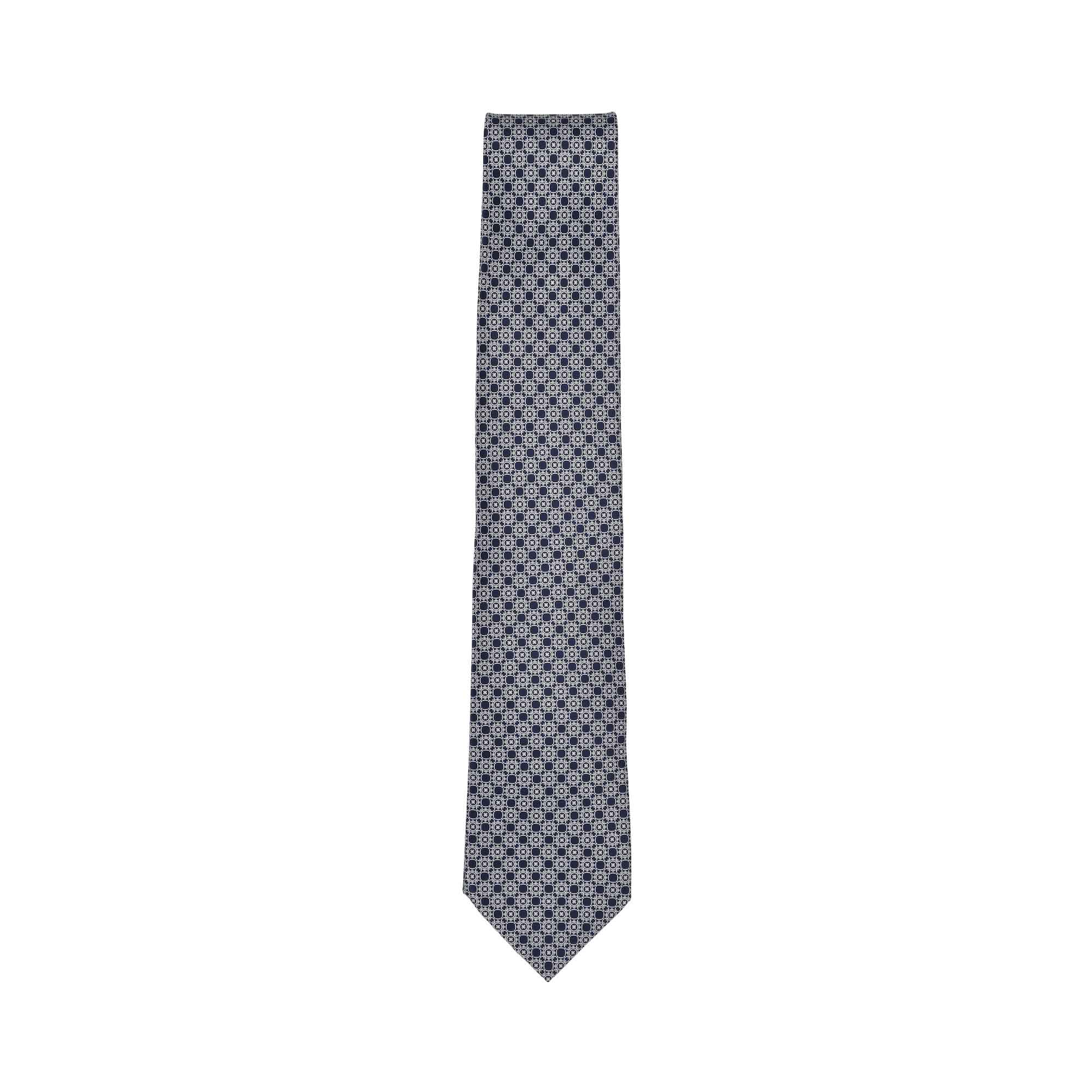 Navy blue and white geometric pattern woven silk tie with a pointed tip, laid flat.