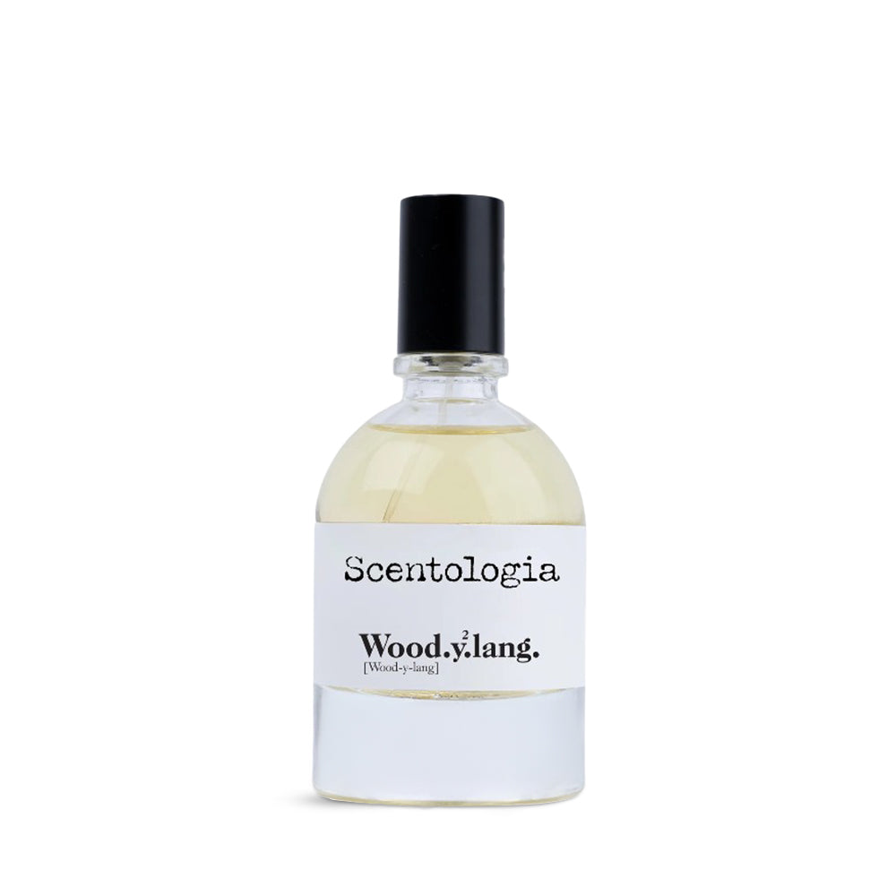 Scentologia Wood.y.lang fragrance, featuring a minimalist glass bottle with a white label and black cap, displayed alongside its artistic branded outer box.