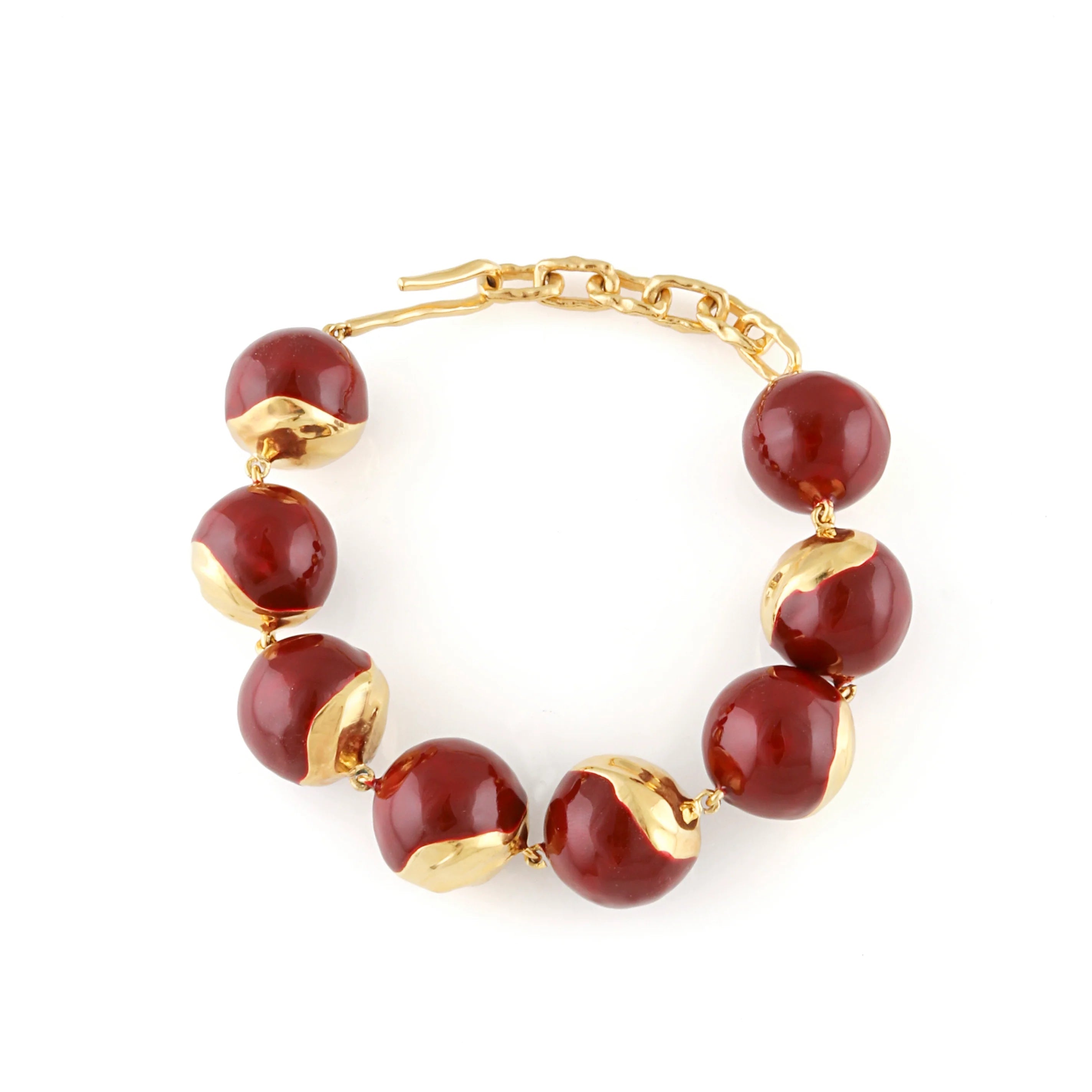 Large orb bracelet with dark red glossy enamel and irregular gold-toned metallic sections, connected by a gold-toned chain an