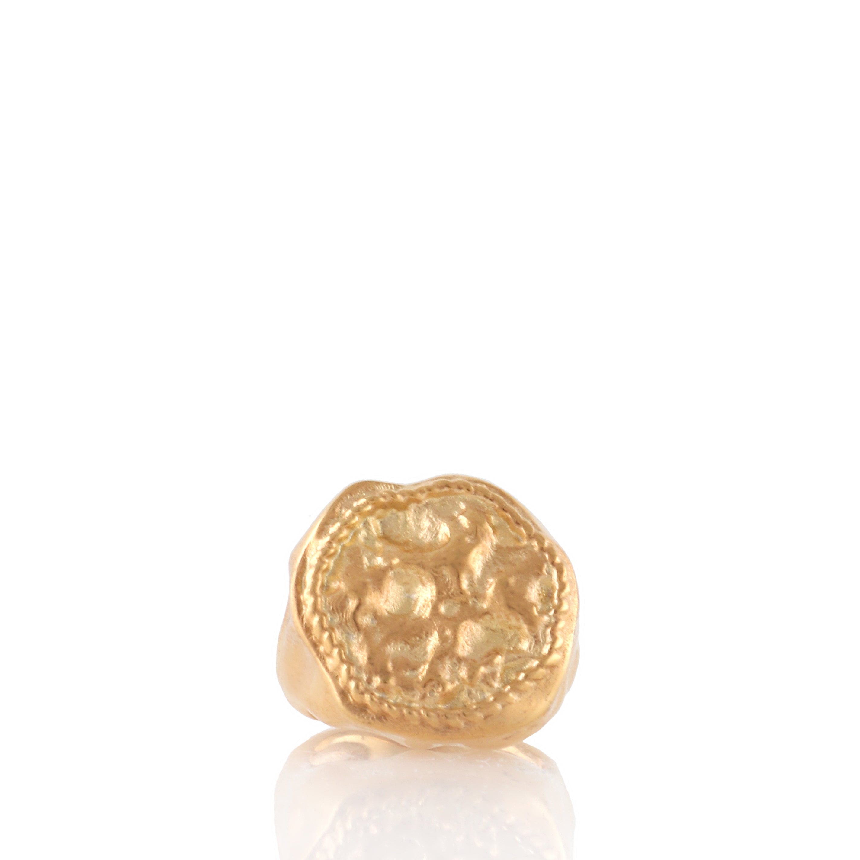 Gold-toned signet ring with an irregular shape and an embossed coin-like motif surrounded by a textured border.