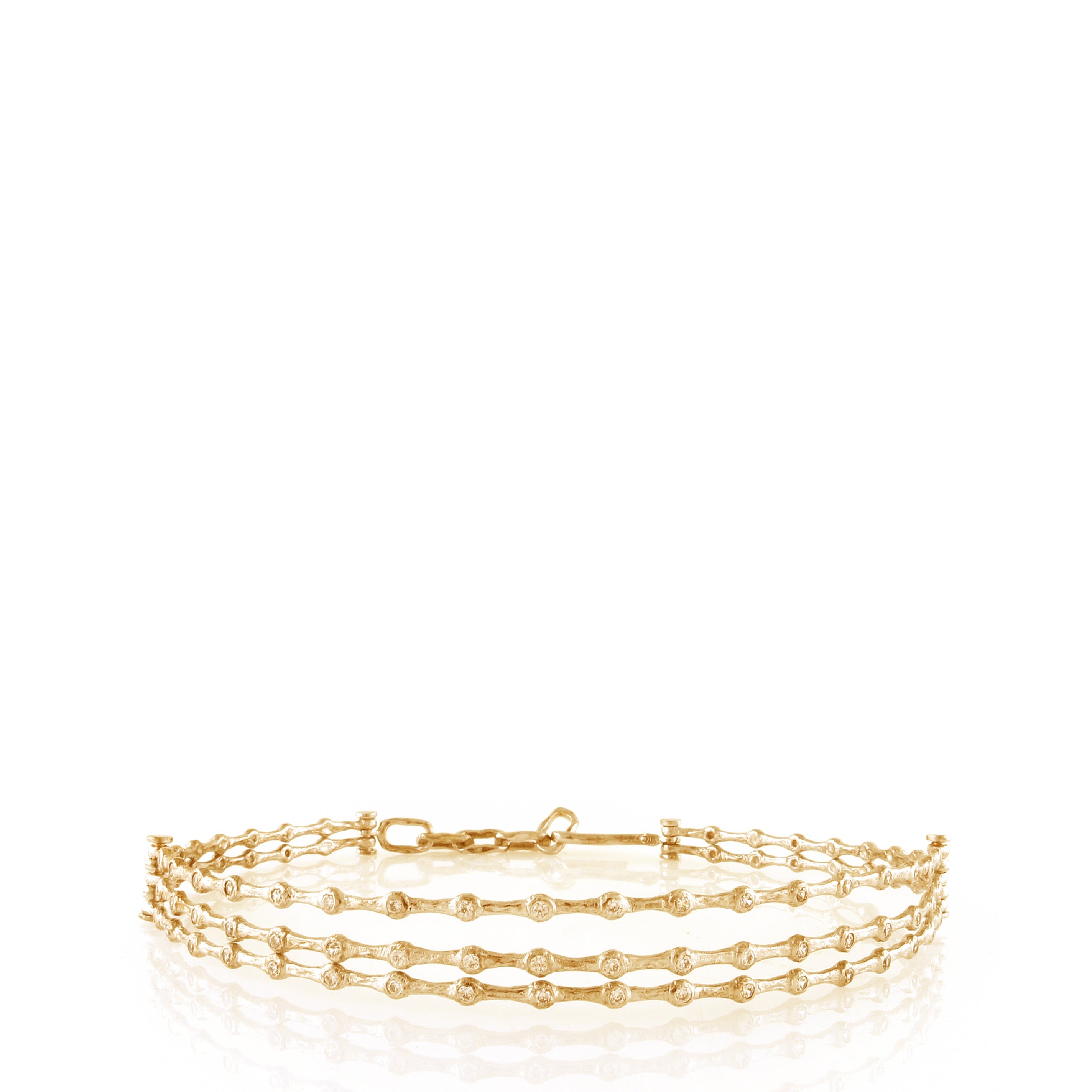 Gold-toned multi-strand choker necklace with wavy textured bands and small clear handset stones, featuring a hook-and-eye cla