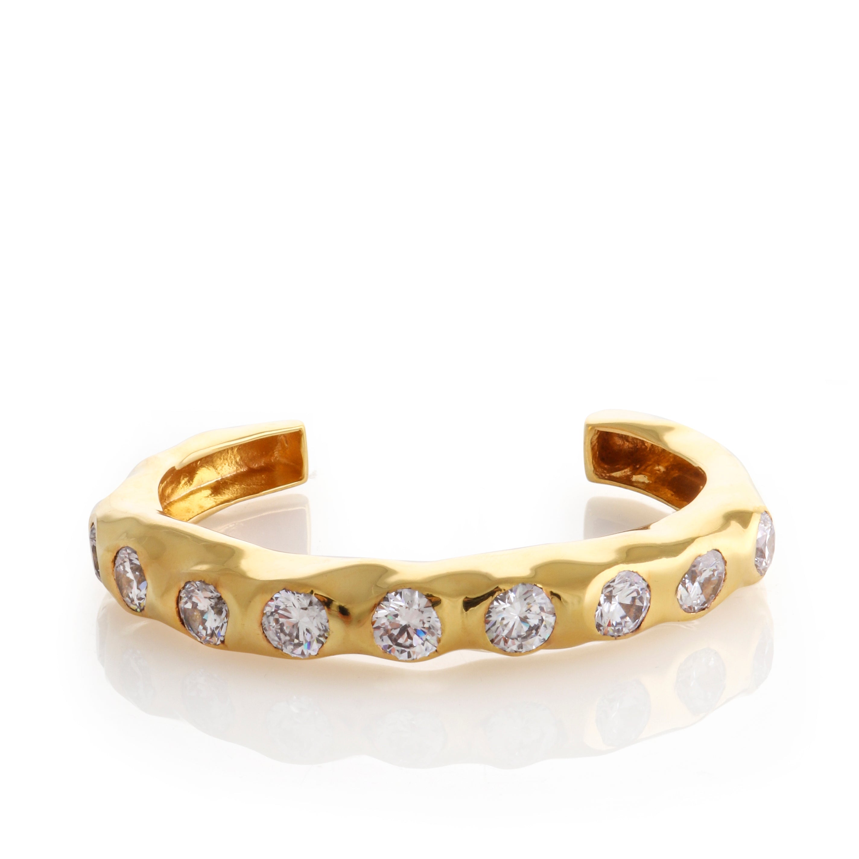 Gold-toned statement wave cuff bracelet with a hammered texture and eight round, clear, handset stones.