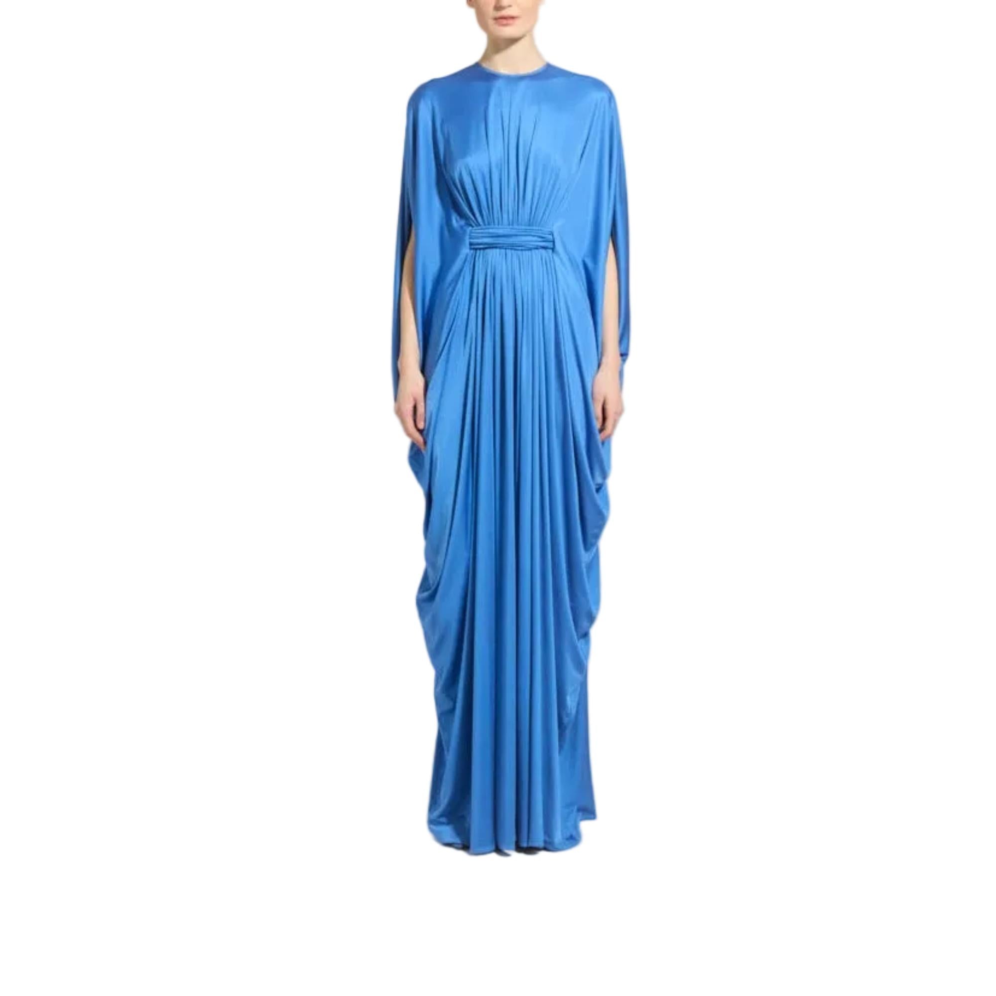 A woman modeling a floor-length royal blue gown with draped sleeves and a matching waist tie, shown against a plain white background.