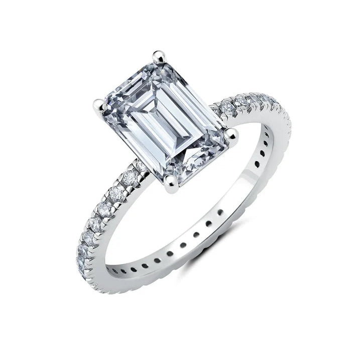 Silver-toned ring with a large clear emerald step-cut centre stone and smaller clear round stones pavé-set along the band.