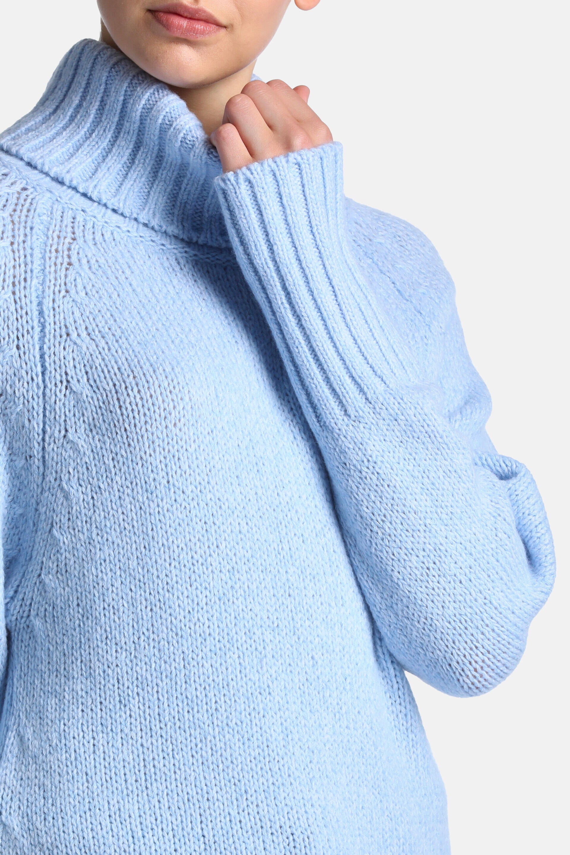 Light blue knitted turtleneck sweater with ribbed collar and cuffs. Subtle cable knit details on the upper body.