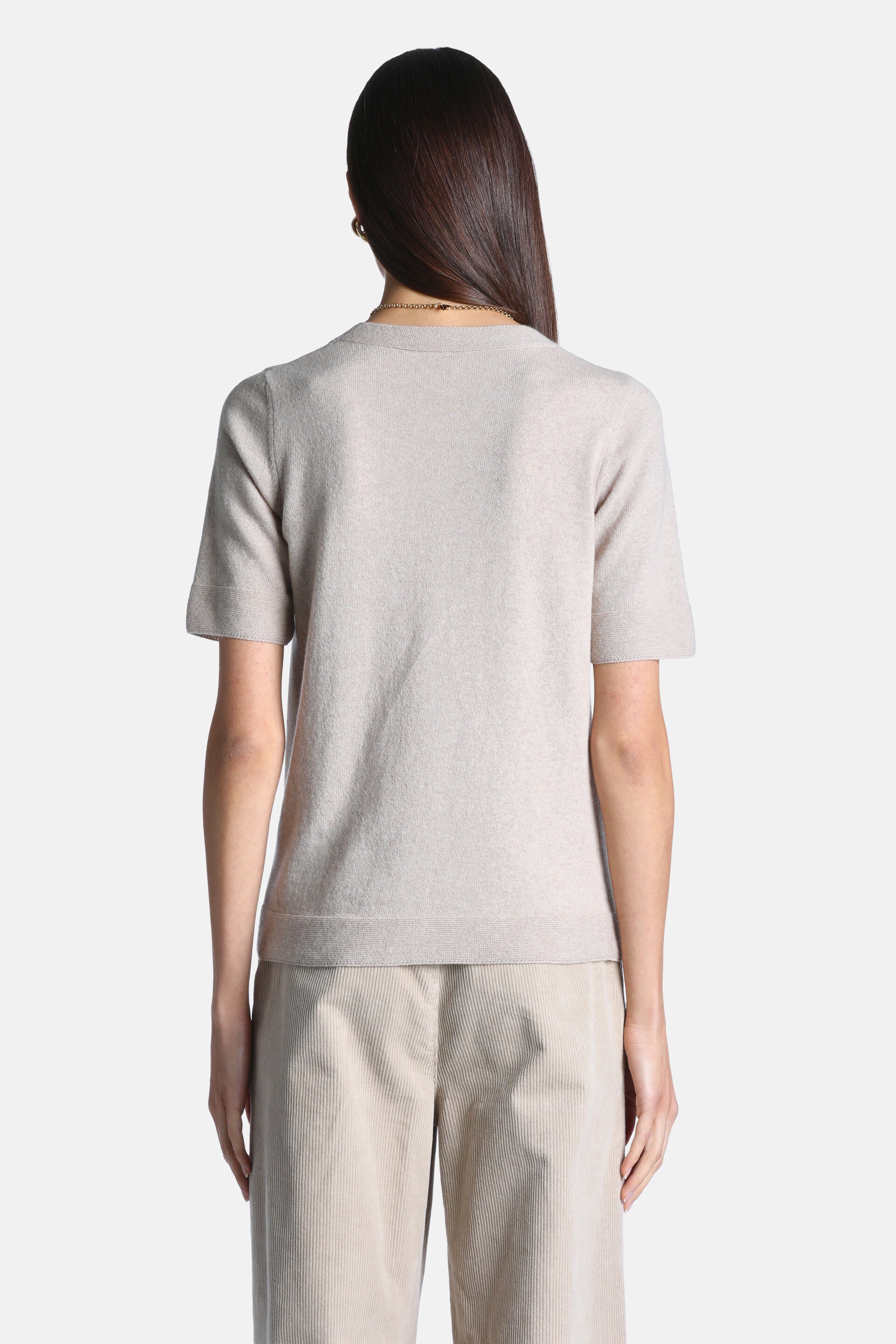 Beige short-sleeved knit pullover with a ribbed crew neck, ribbed cuffs, and ribbed hem, shown from the back.