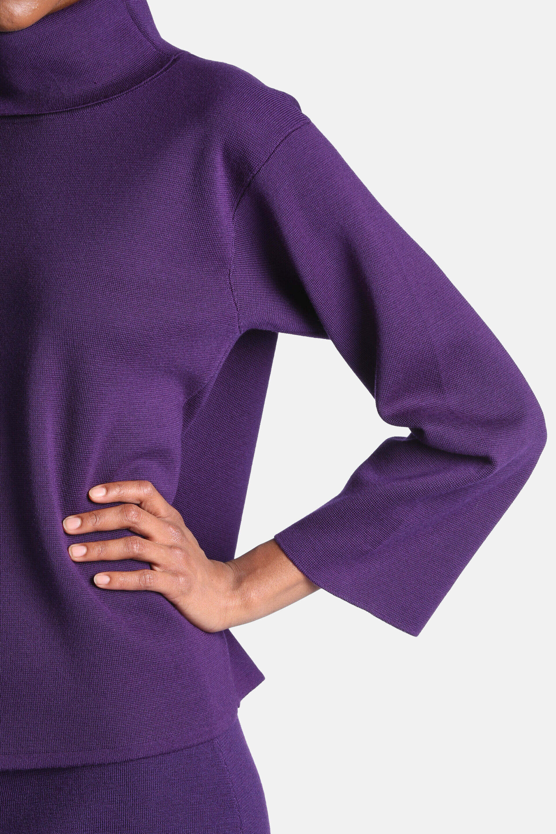 Deep purple knit tunic with a high turtleneck and wide, long sleeves.