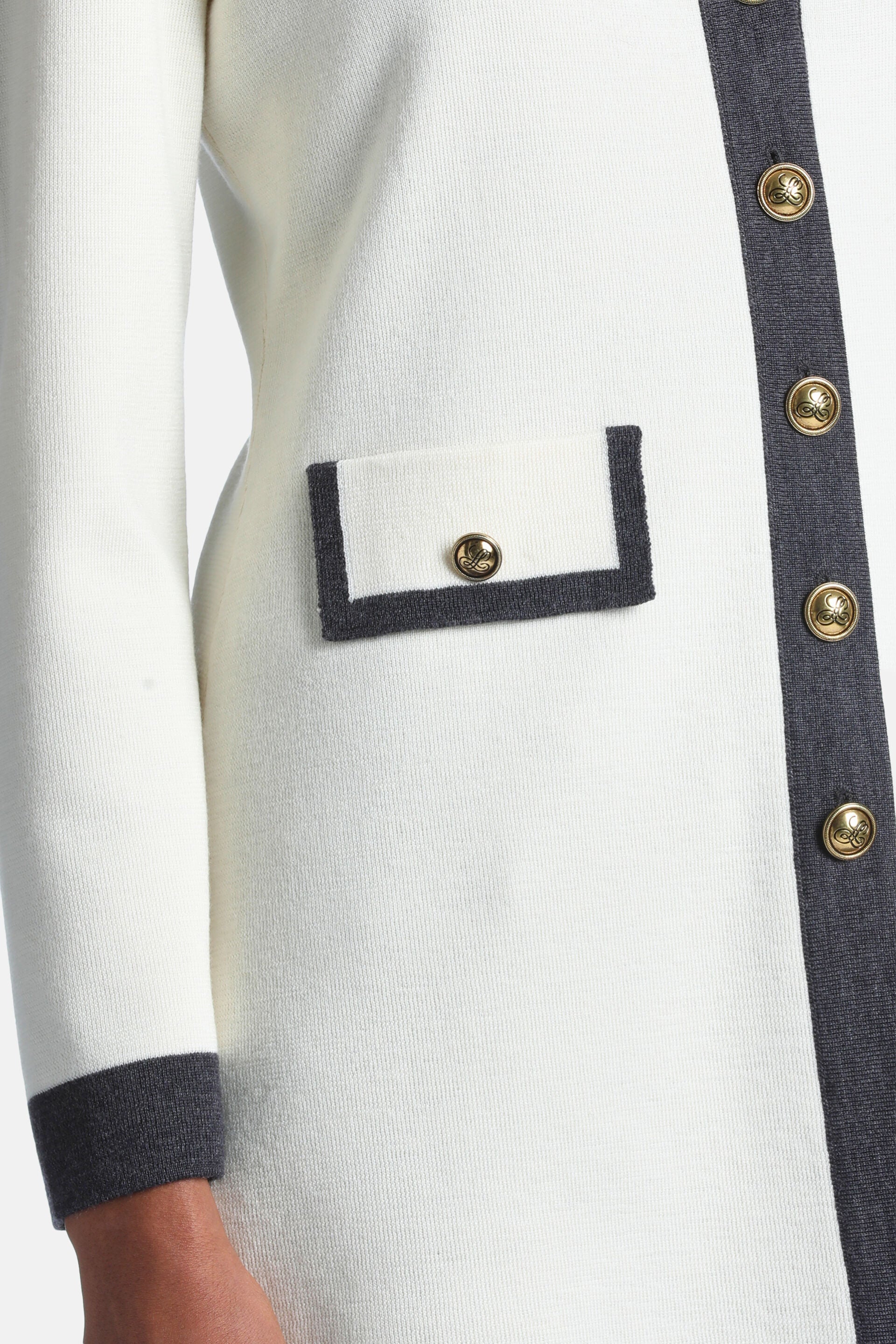 Off-white cardigan with dark gray trim on placket, cuffs, and a patch pocket. Gold-toned emblem buttons.