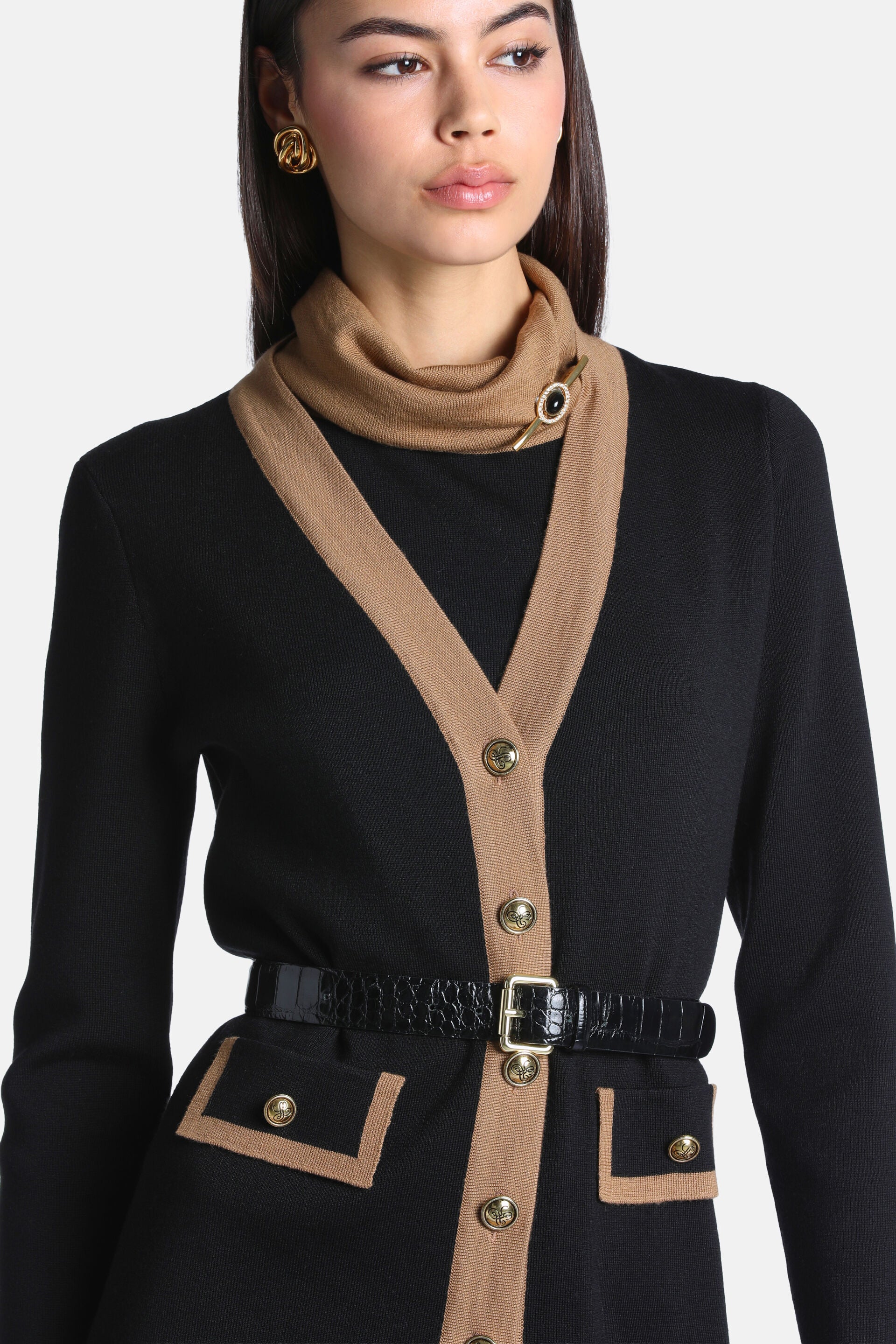 Black knit cardigan with camel V-neck trim, gold-toned buttons down the front, and two front patch pockets with camel trim an