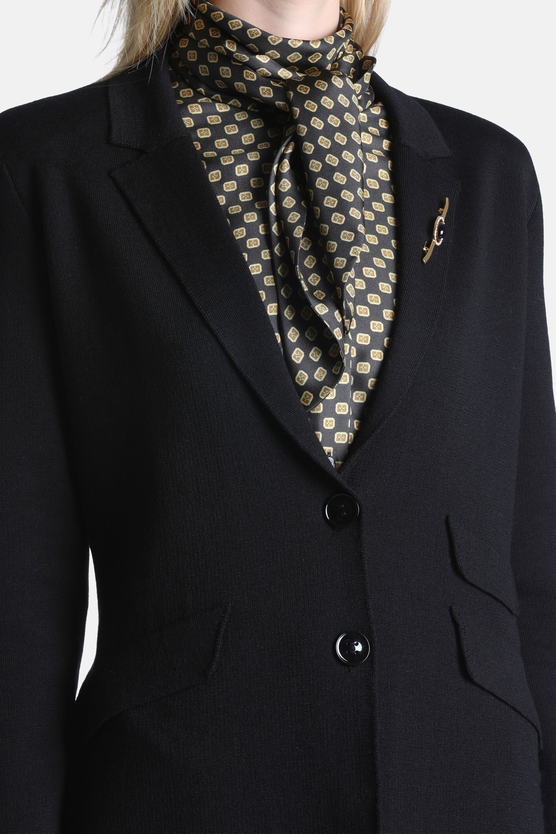 Black knit blazer jacket with notched lapels, two black button closure, and two front patch pockets with curved tops.
