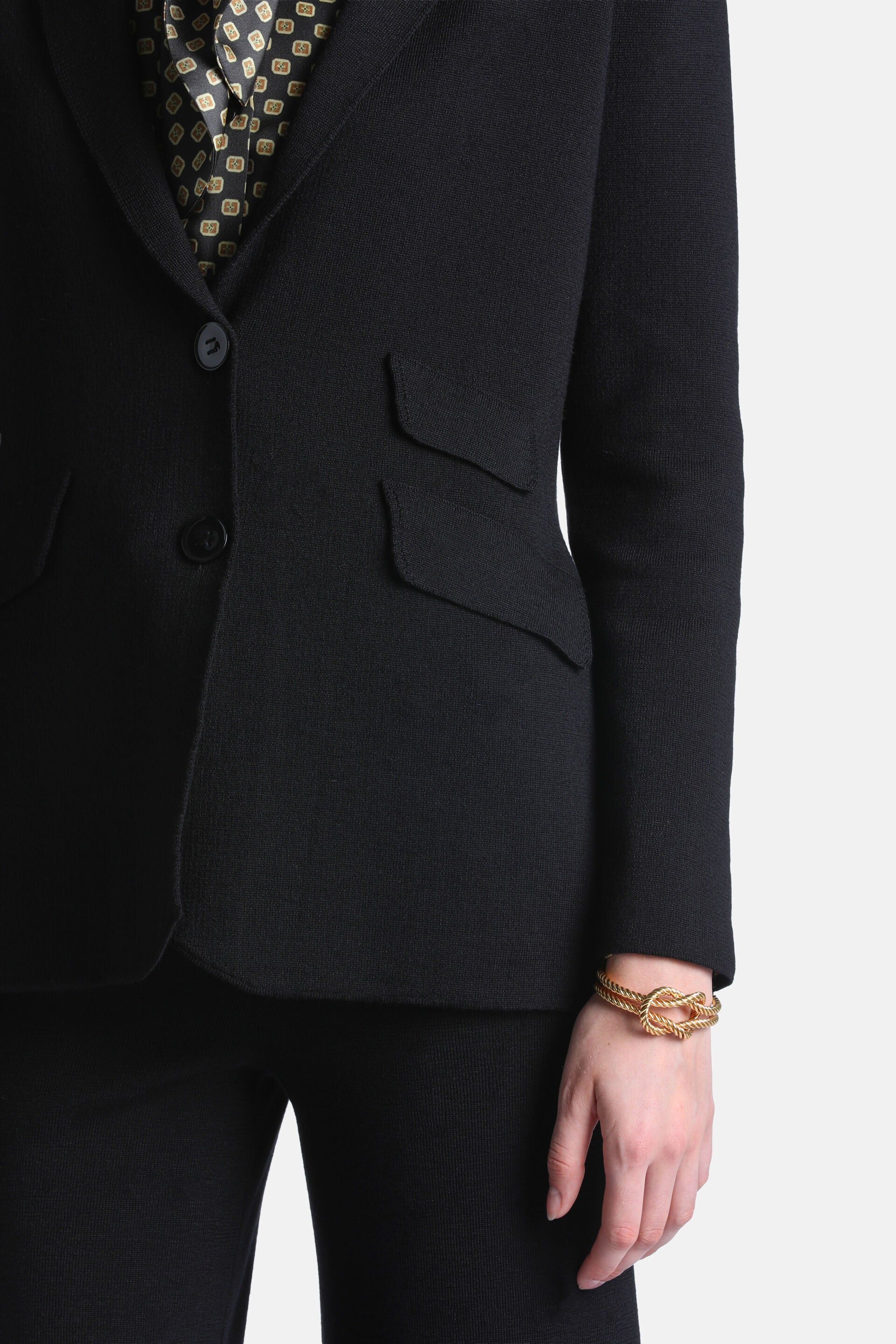Black knit jacket with notched lapels, two black buttons, and two front flap pockets with curved edges.