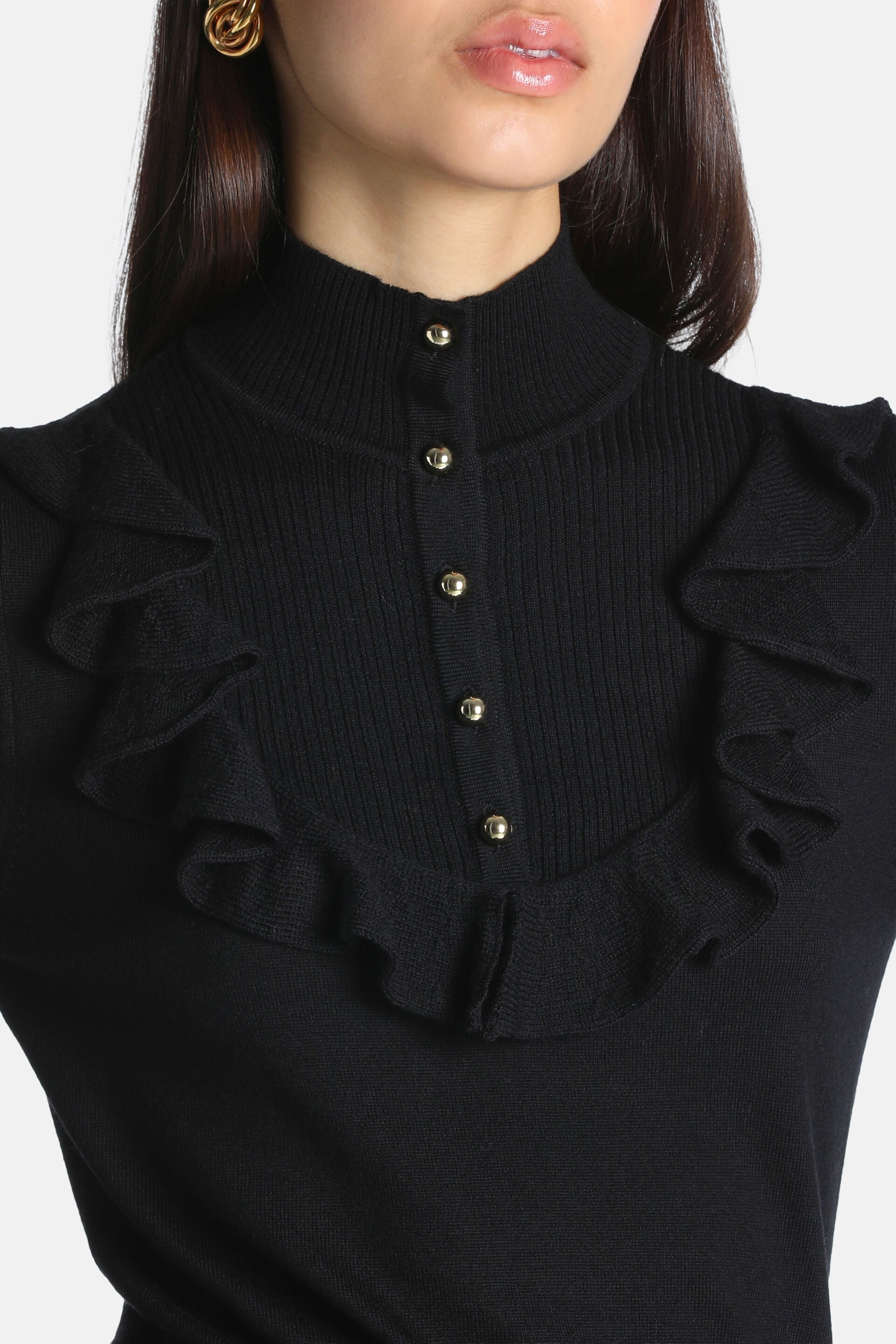 Black ribbed knit pullover with a mock neck, a front placket with five gold-toned buttons, and ruffles around the placket.