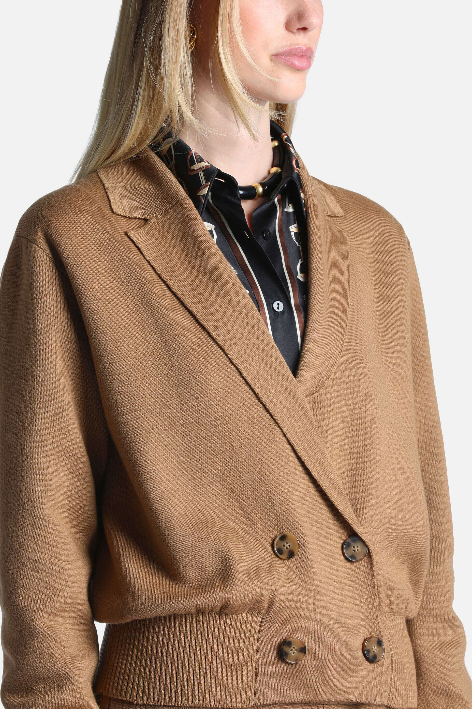 Camel knit double-breasted jacket with notched lapels, four tortoise-shell buttons, and a ribbed hem.