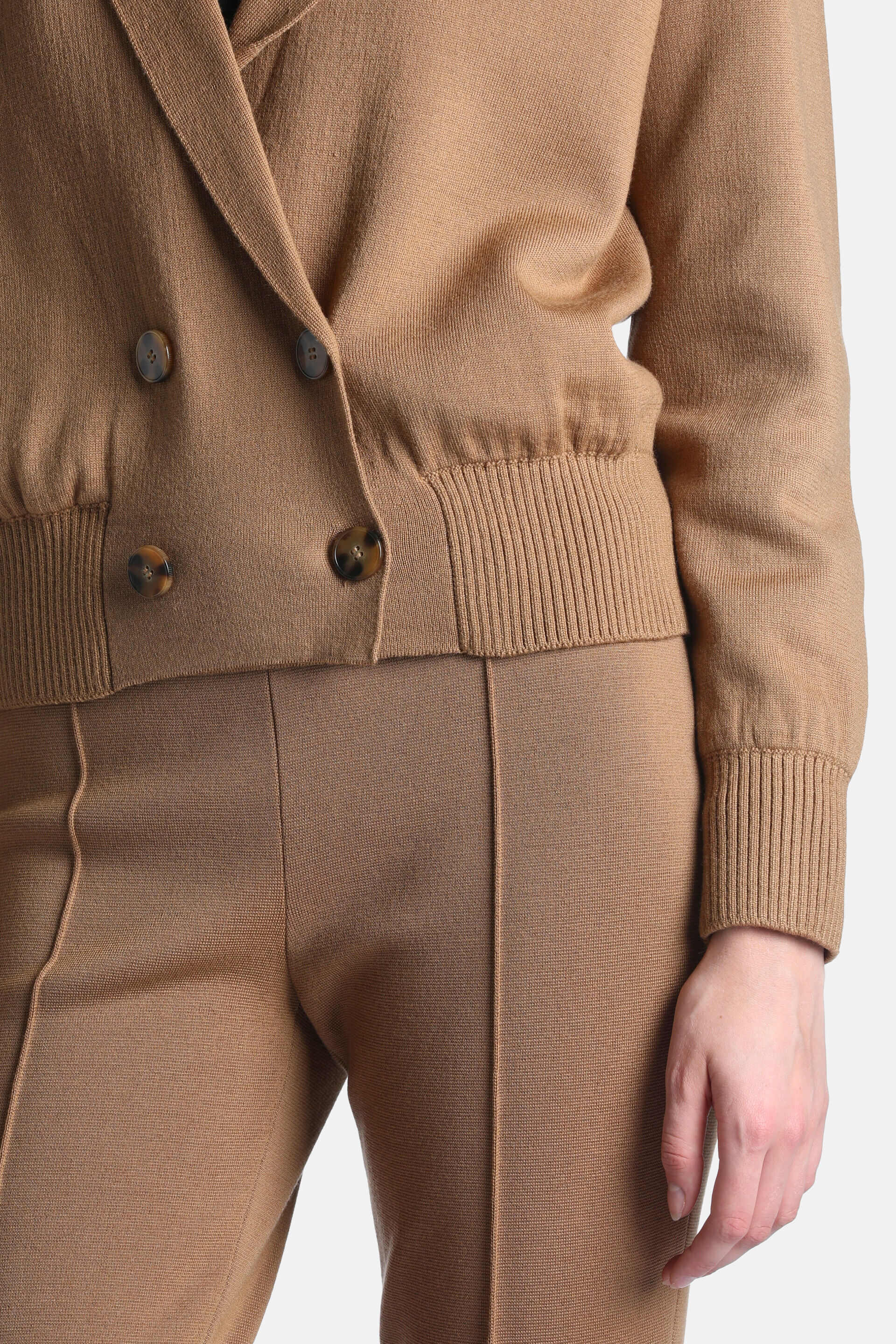 Camel knitted double-breasted jacket with wide lapels, four tortoiseshell buttons, ribbed elasticated hem, and ribbed cuffs.