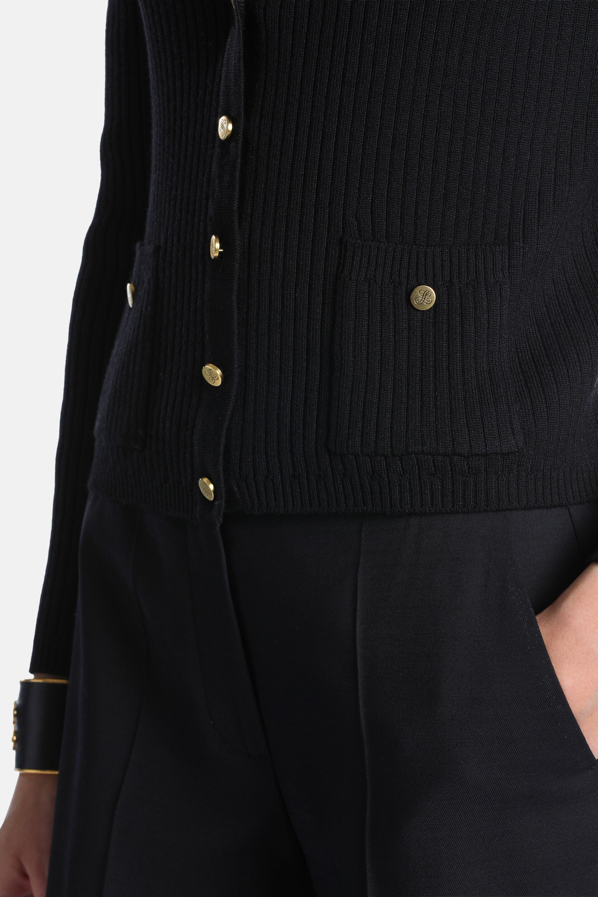 Black ribbed knit jacket with long sleeves, gold-toned buttons down the front, and two front patch pockets with gold-toned em