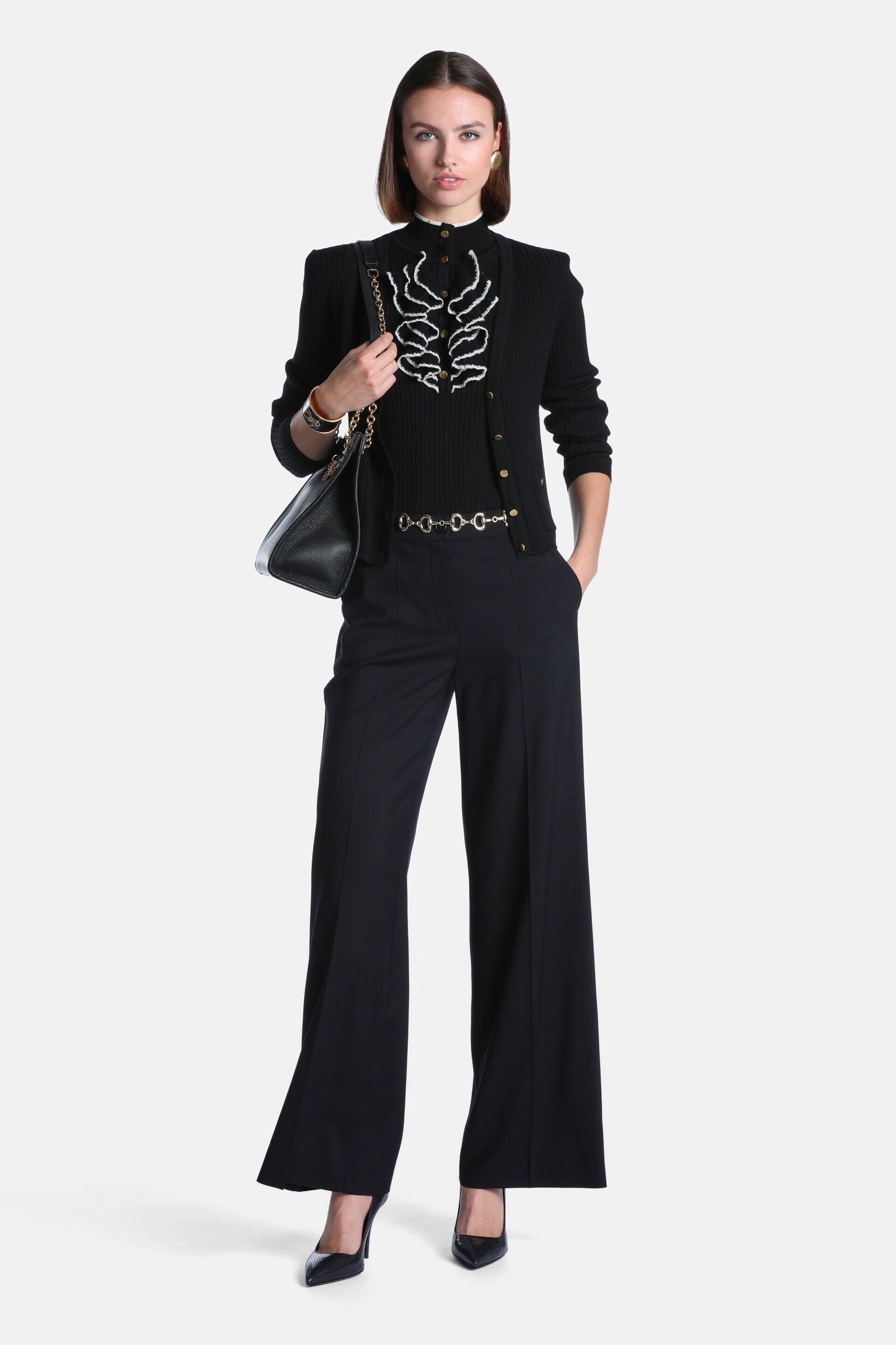 Black ribbed knit cardigan jacket with structured shoulders, gold-toned button front, and white wavy embroidery on the chest.