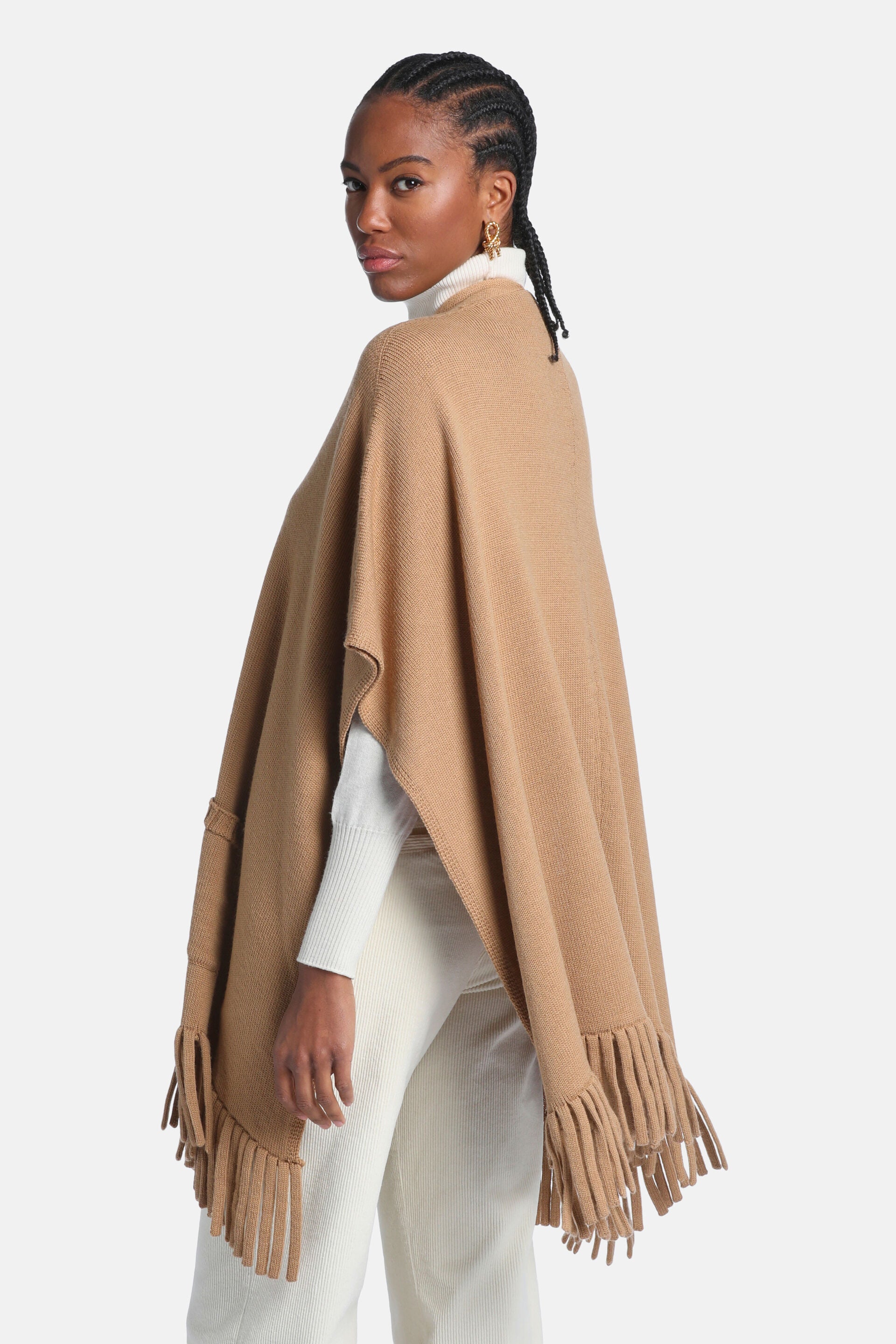 Camel knitted mantle with a loose fit, round neck, and fringed hem. Features a small patch pocket on the left side.