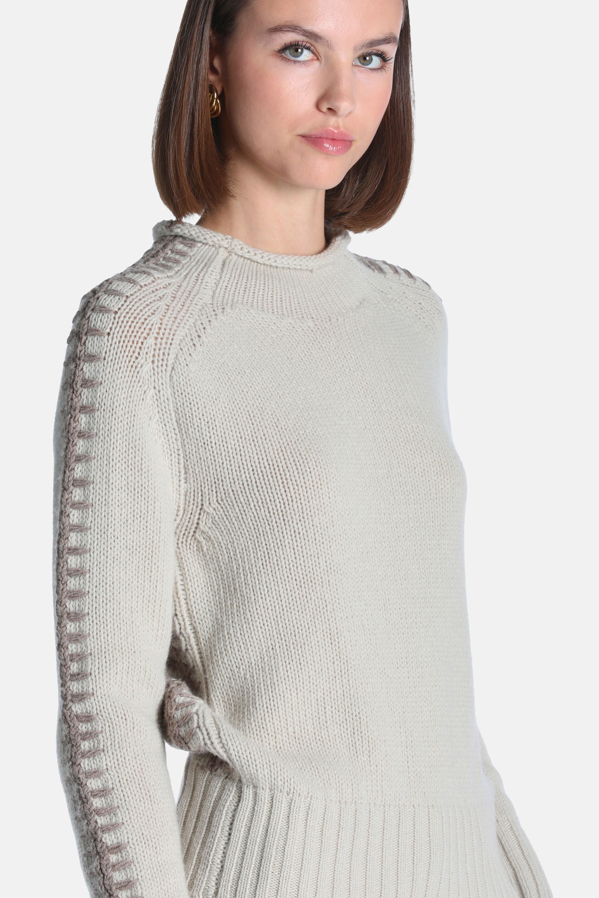 Light beige knit pullover with a mock neck, raglan sleeves, and decorative darker beige stitching along the shoulder and oute