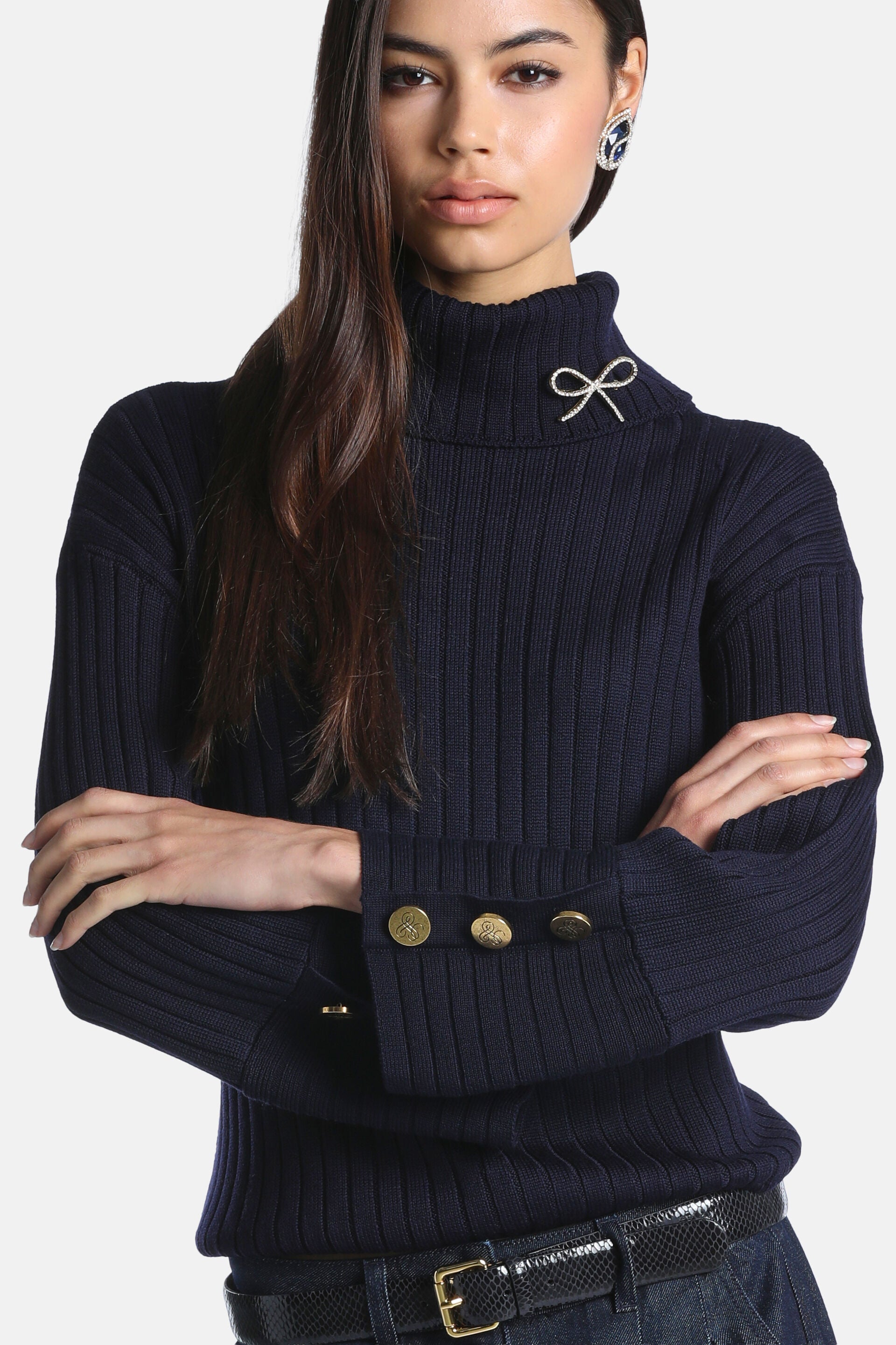 Navy blue rib-knit turtleneck pullover with a sparkly silver-toned bow brooch on the collar and gold-toned buttons on the cuf