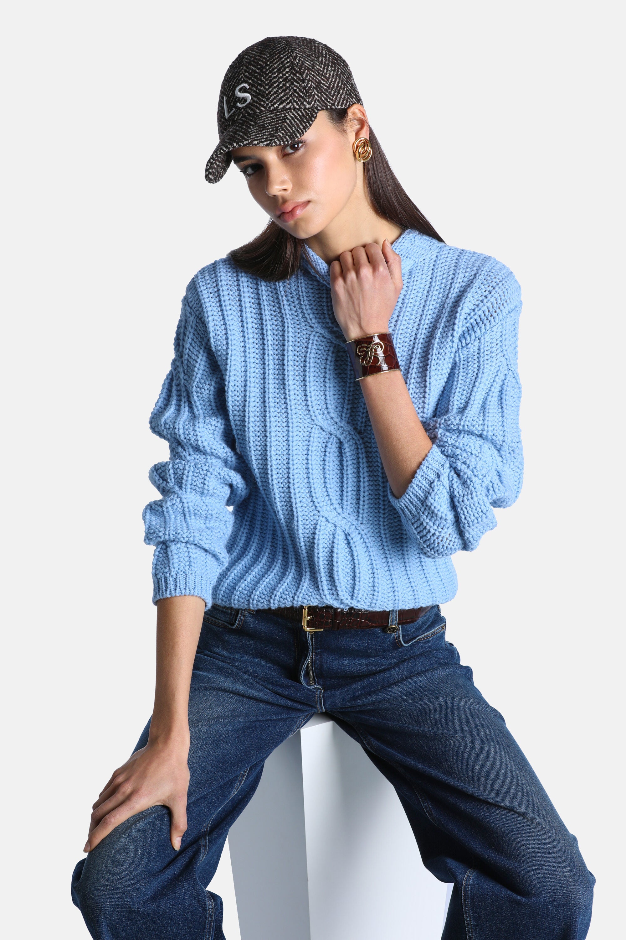 Light blue chunky knit pullover with a crew neck, featuring vertical ribbed and cable knit patterns on the body and sleeves.