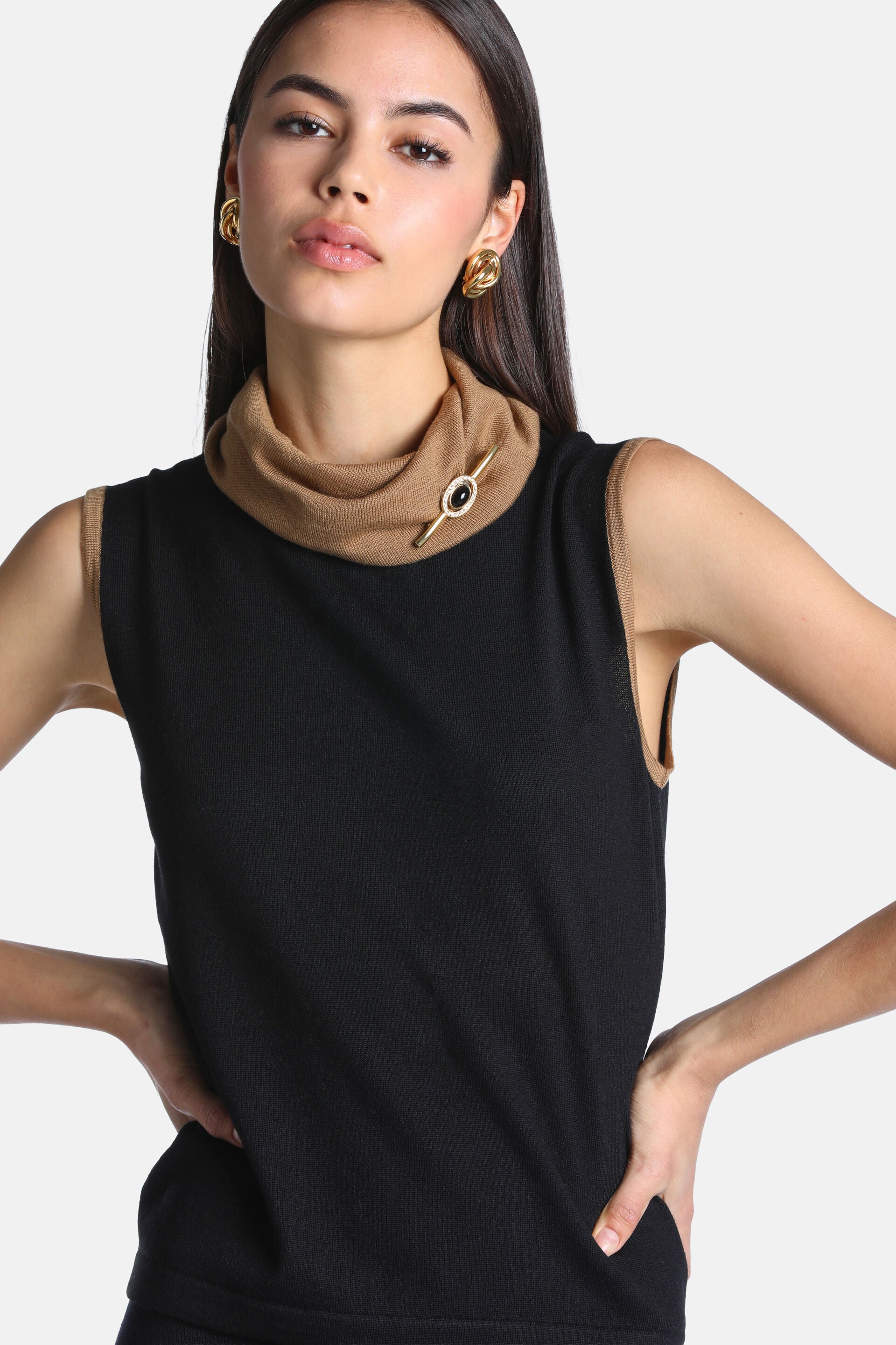 Black sleeveless knit sweater with a camel cowl neck and camel trim on the armholes.
