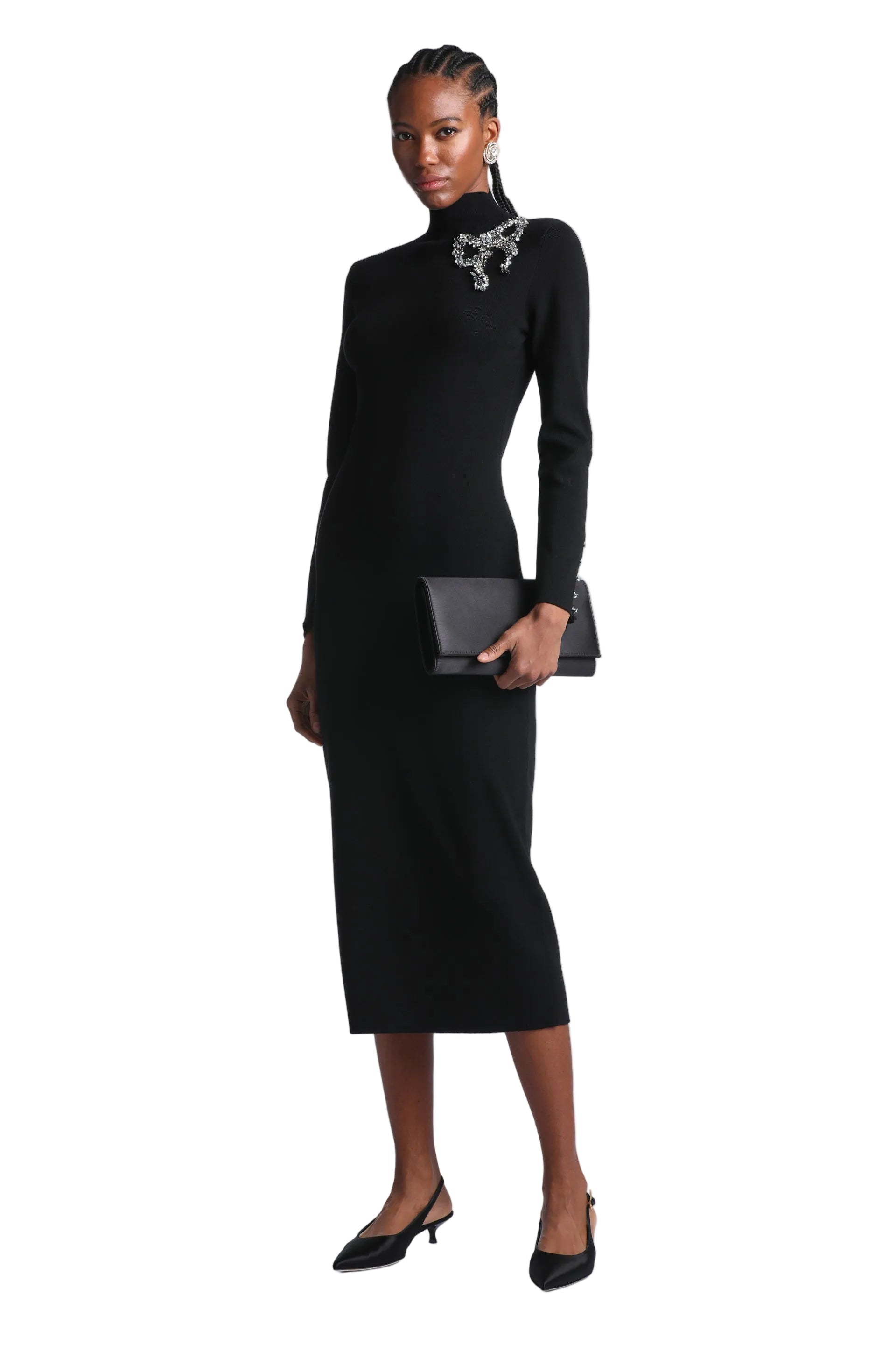 Black knit midi dress with a high turtleneck, long sleeves, and a silver-toned embellished bow brooch at the left shoulder.