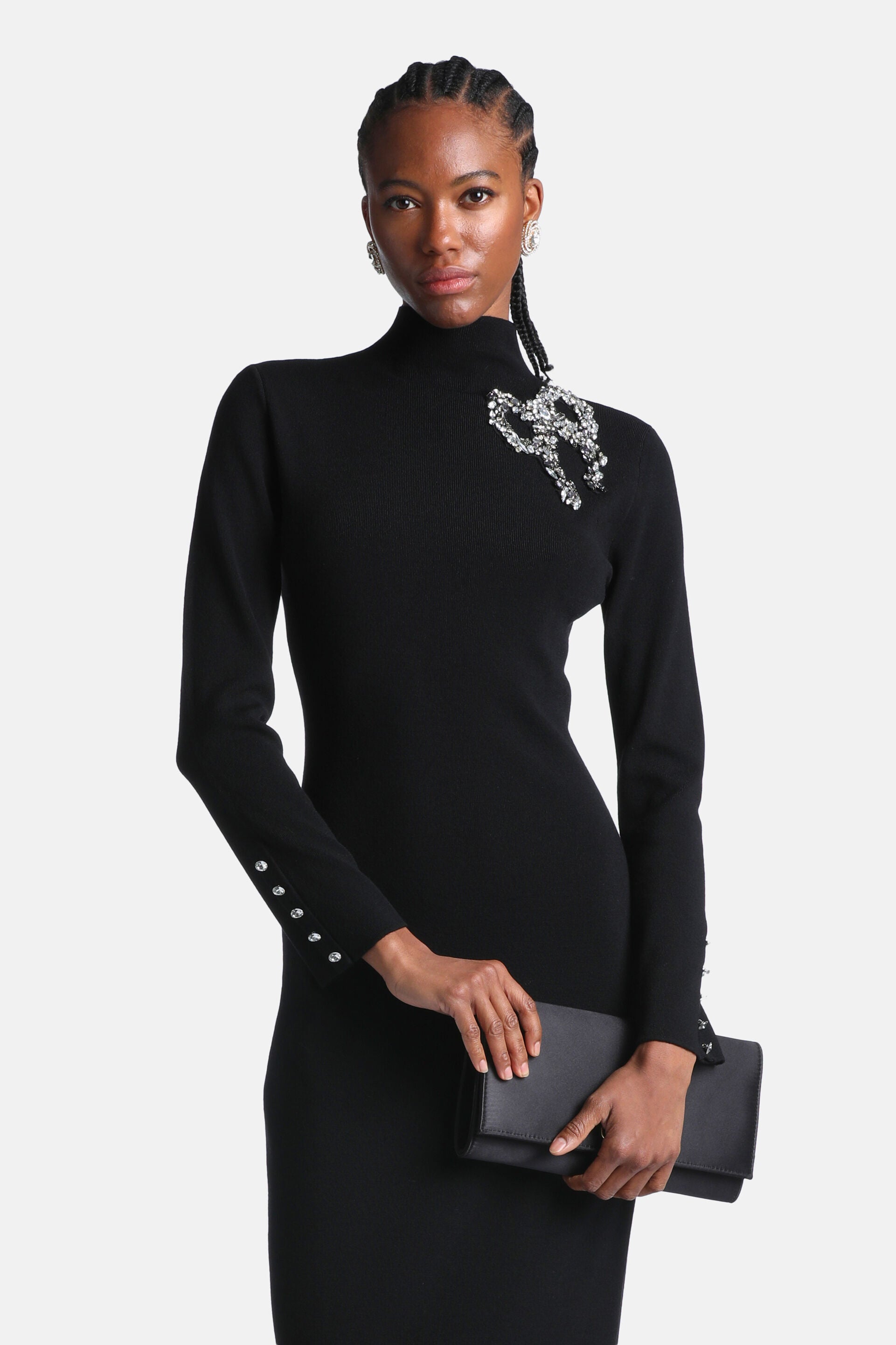 Black knit turtleneck dress with long sleeves. Large rhinestone embellishment on left shoulder, four rhinestone buttons on cu