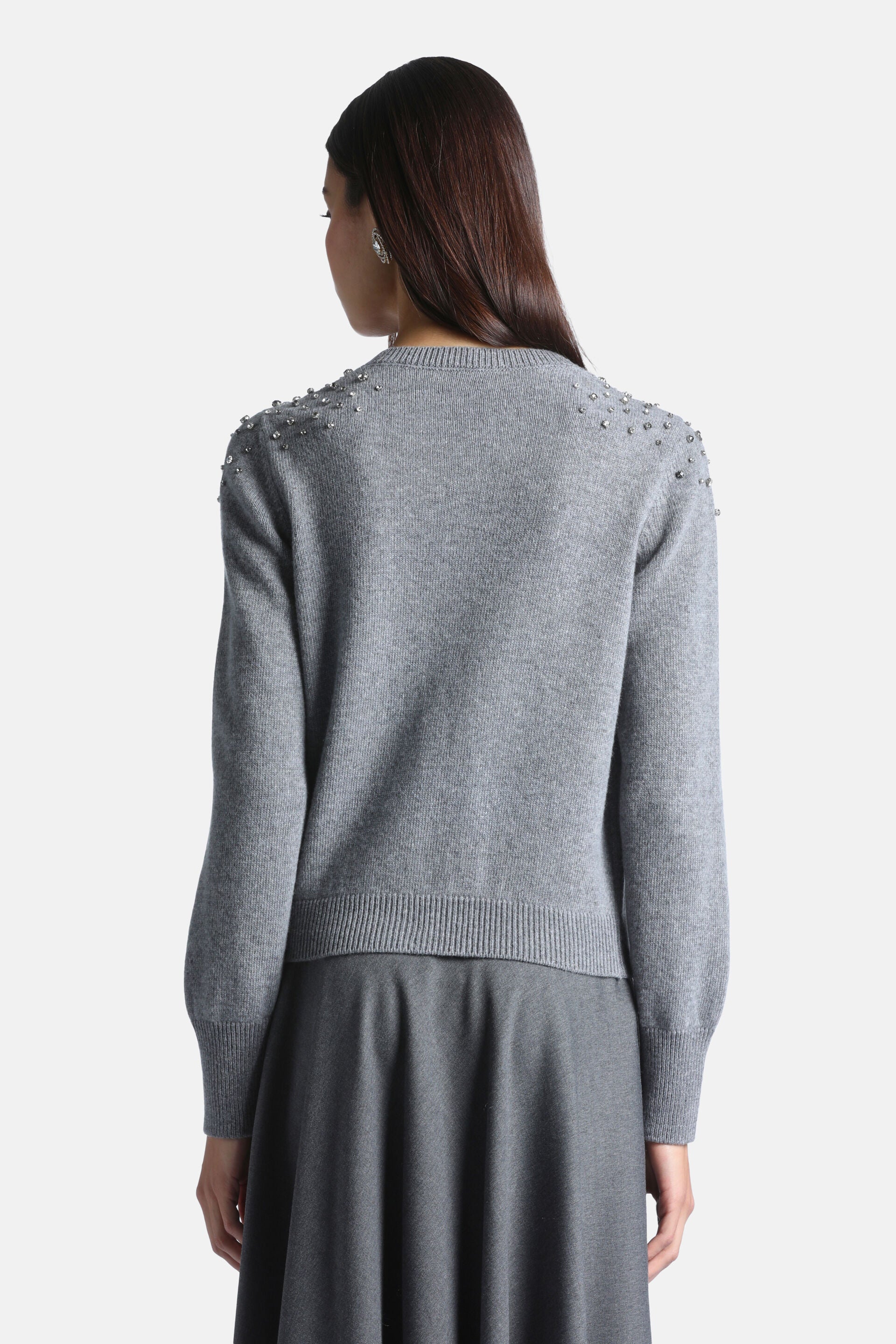 Grey knit cardigan, back view, with round neck, long sleeves, ribbed cuffs and hem. Shoulders embellished with silver-toned s