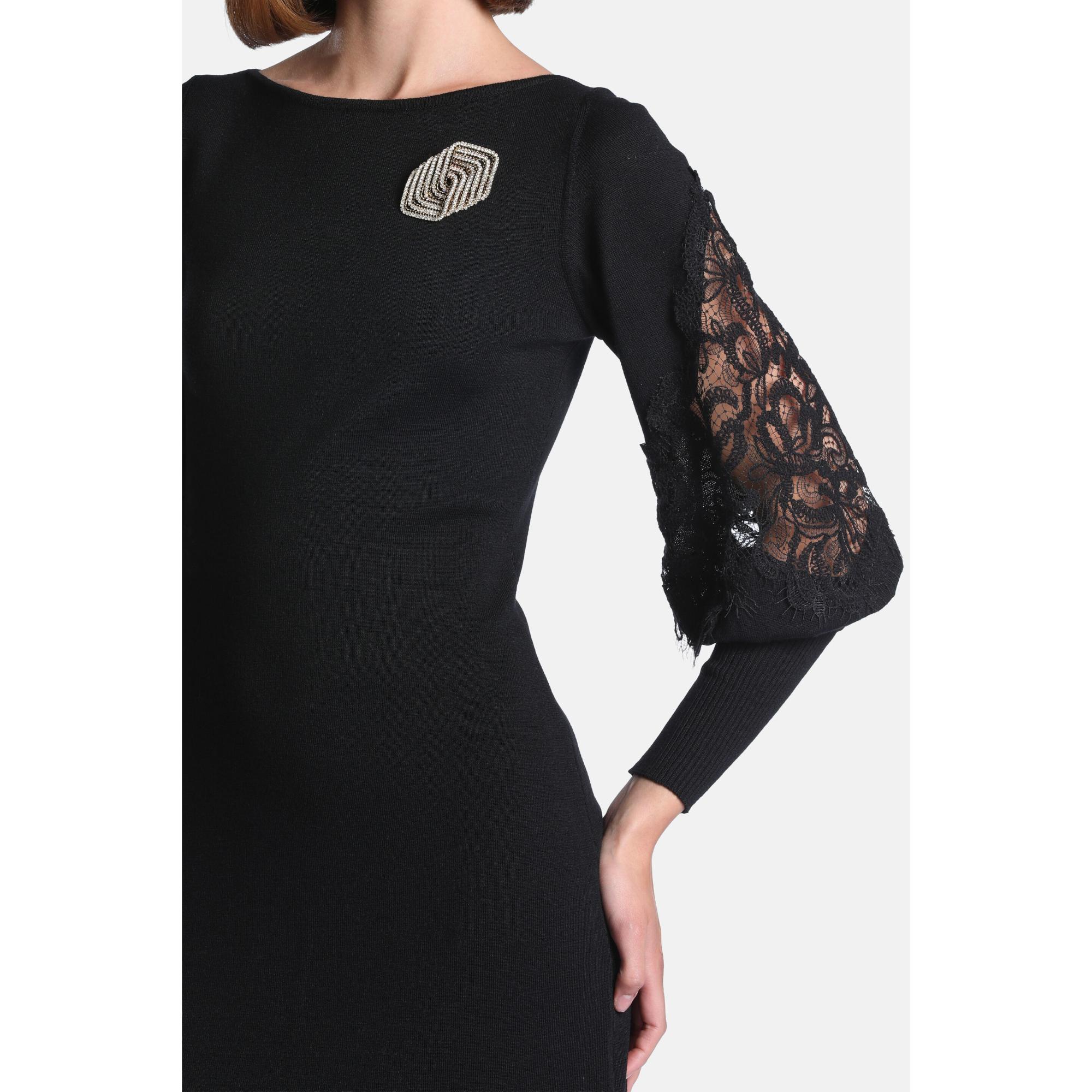Black knit dress with puffed lace sleeves and ribbed cuffs, adorned with a geometric two-toned brooch.