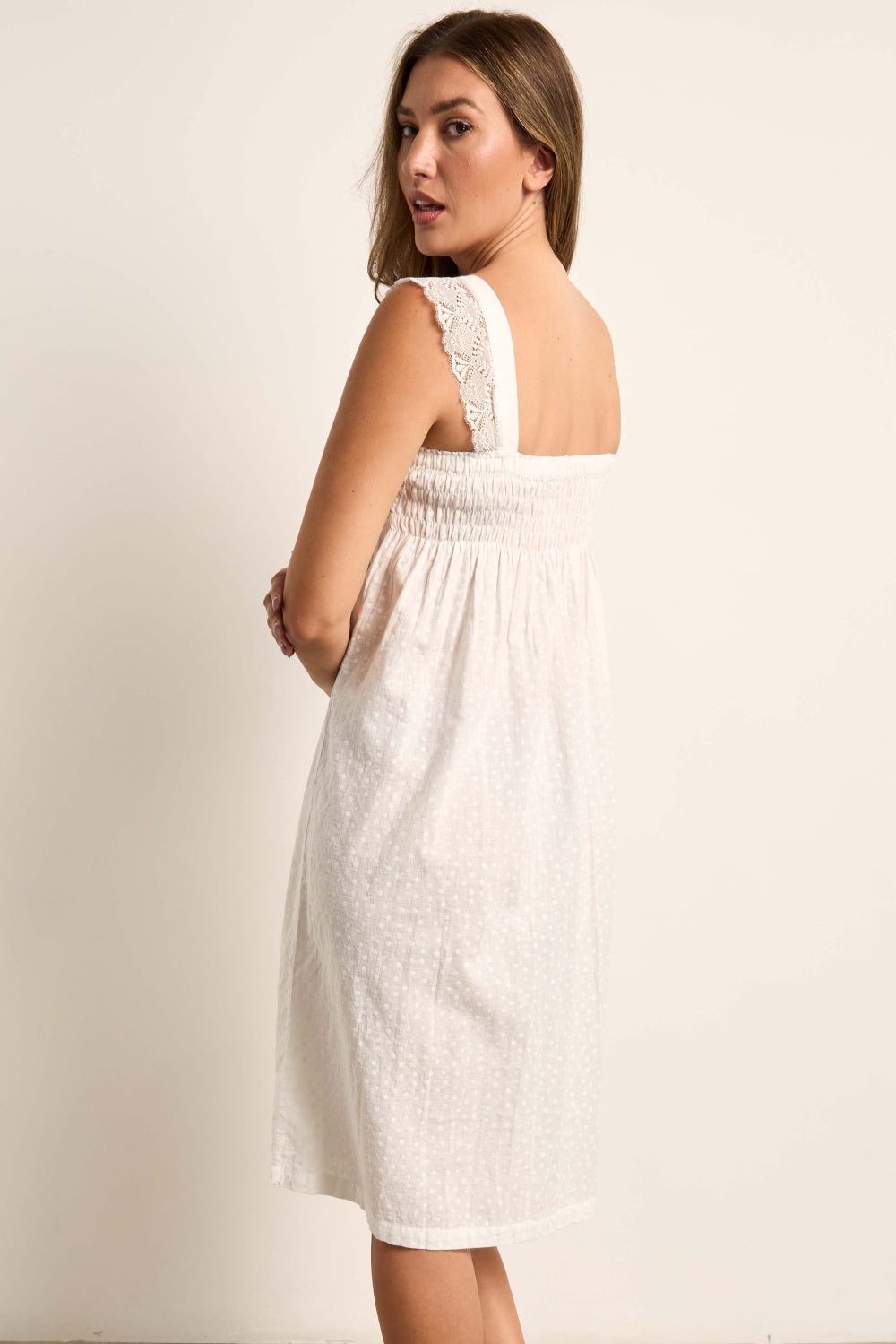 Cream strappy dress. Right shoulder strap has lace trim. Smocked bodice, loose skirt with subtle dotted texture.