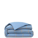 Blue duvet cover with a grid pattern of white, black, and tan stripes. Matching solid blue pillow case.