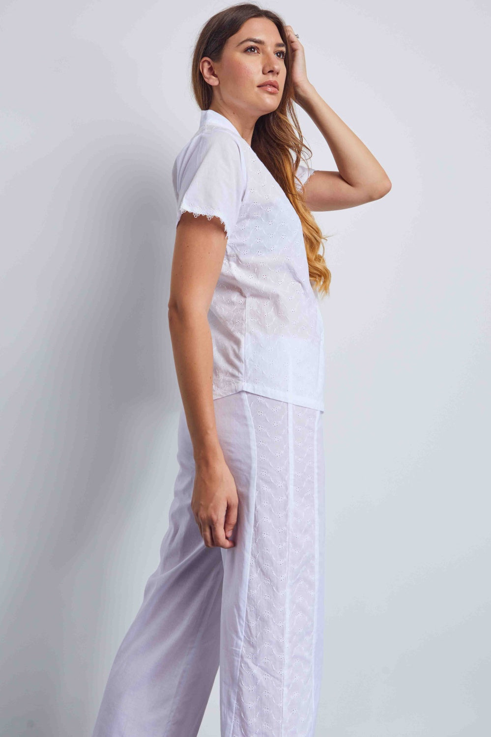 White short-sleeve button-up shirt and wide-leg pants set. Both pieces feature sheer fabric with floral eyelet embroidery and