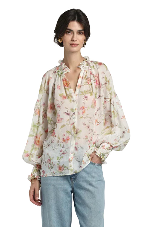 Off-white sheer floral shirt with peach and green flowers, ruffled V-neck, long voluminous sleeves, and ruffled cuffs.