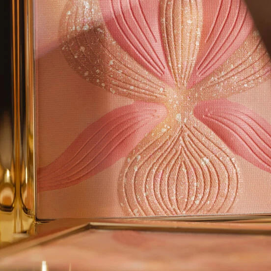 Gold-toned compact with an embossed orchid design in shimmery pink and peach powder, accented with white glitter.