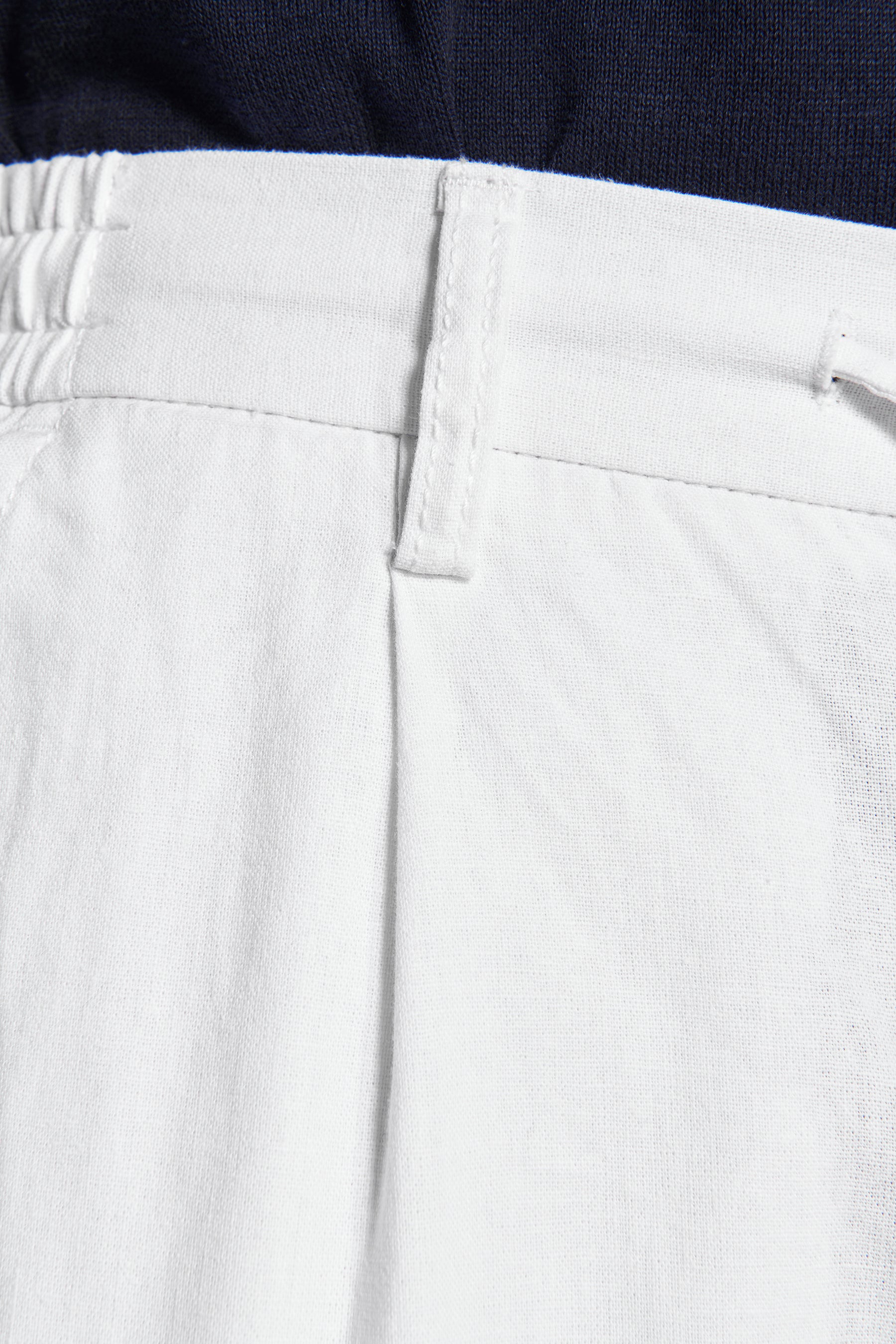 White trousers with an elasticated back waistband, a flat front waistband with a belt loop, and a front pleat.