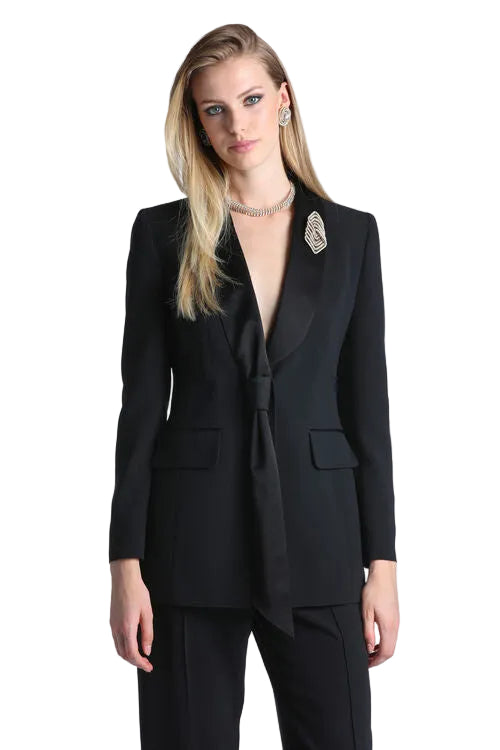 Black women's tailored blazer with deep V-neckline, satin notched lapels, and a front tie detail. Features two flap pockets.