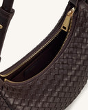 Dark brown woven crossbody bag with a curved shape, gold-toned top zipper, and matching pull. Dark brown interior lining and