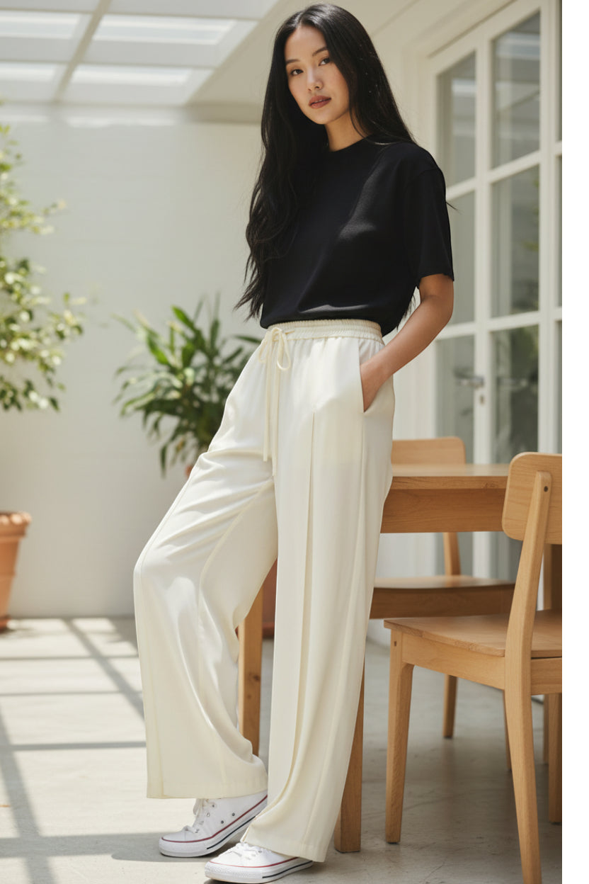Ecru wide-leg trousers with an elasticated drawstring waist, side pockets, and front pleats.